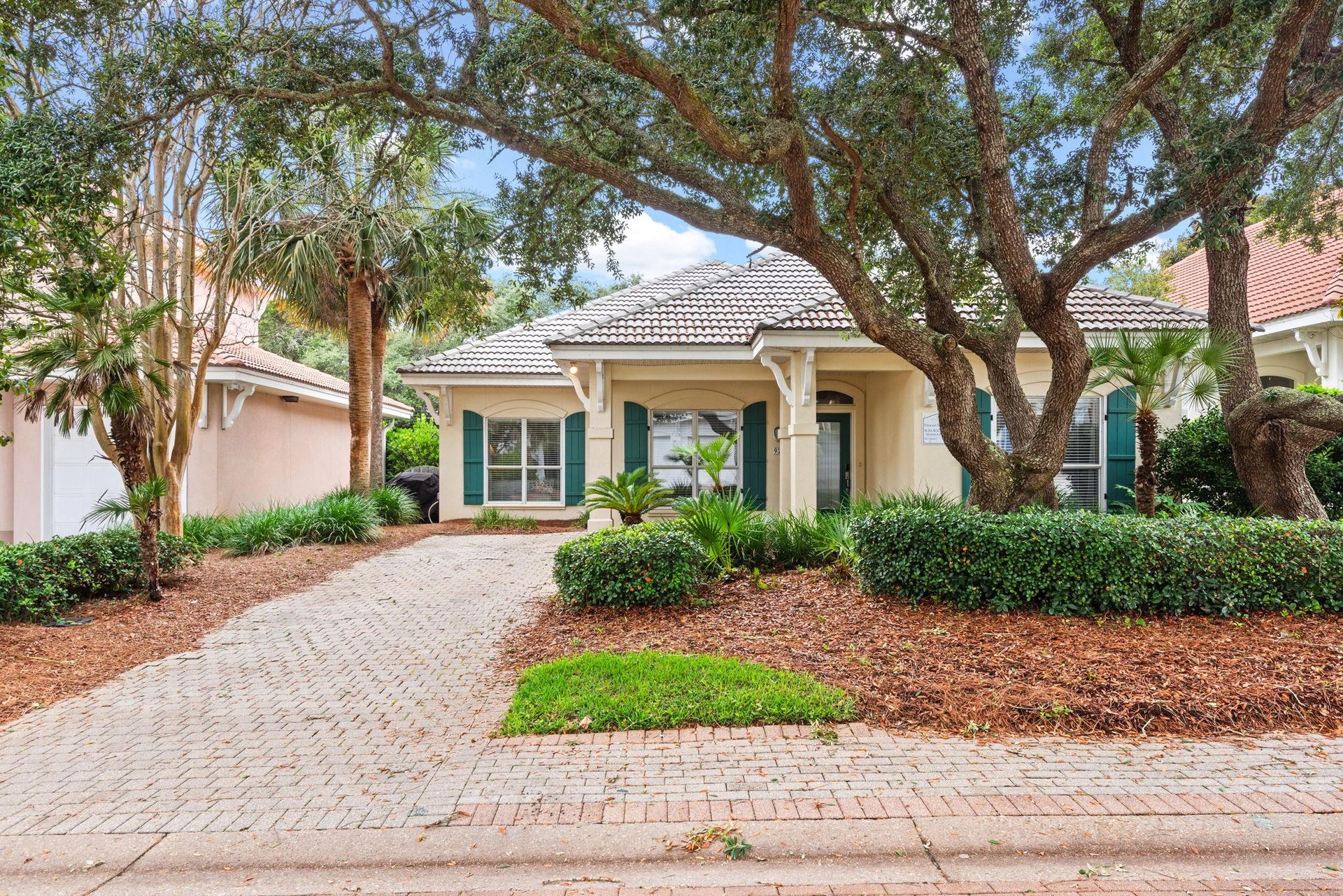 Charming singlestory villa framed by mature trees and tropical landscaping, offering a welcoming entrance.