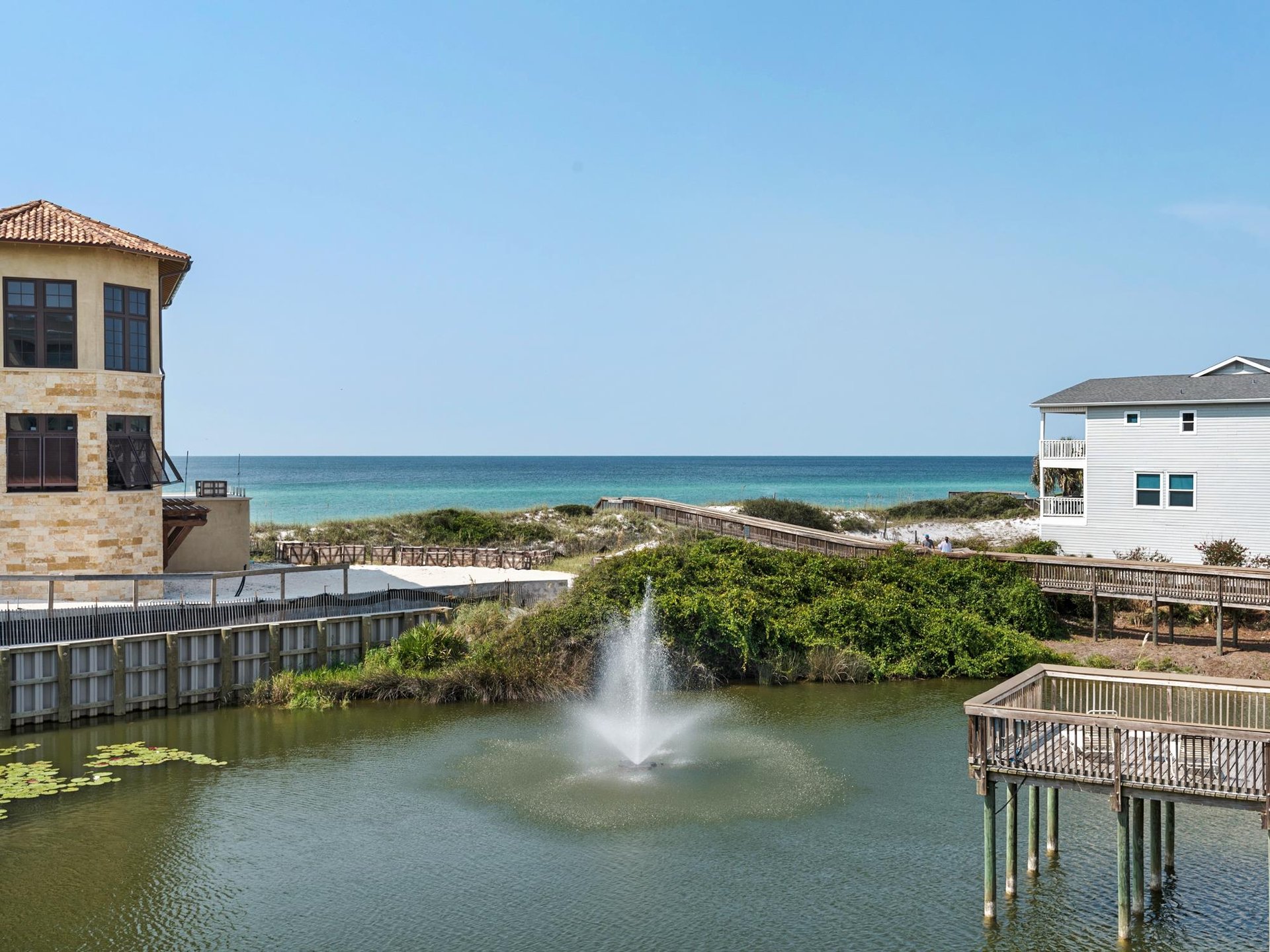Coastal property featuring direct beach access via boardwalk, tropical landscaping, and stunning ocean views in a serene beachfront community.