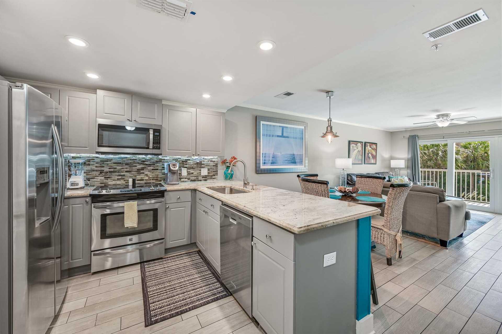 Your openconcept kitchen and living area flows seamlessly with modern gray cabinetry, granite countertops, and stainless steel appliances.