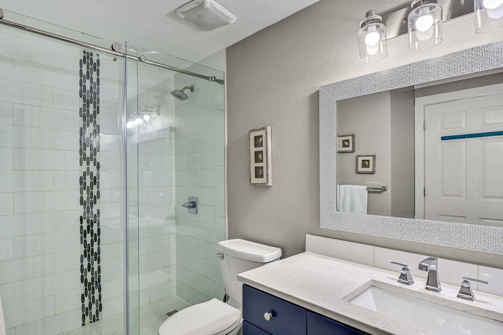 Step into your modern Primary bathroom featuring a spacious walkin shower, sparkling tile accents, and contemporary finishes. Fresh towels and ample lighting set the stage for a refreshing start to y