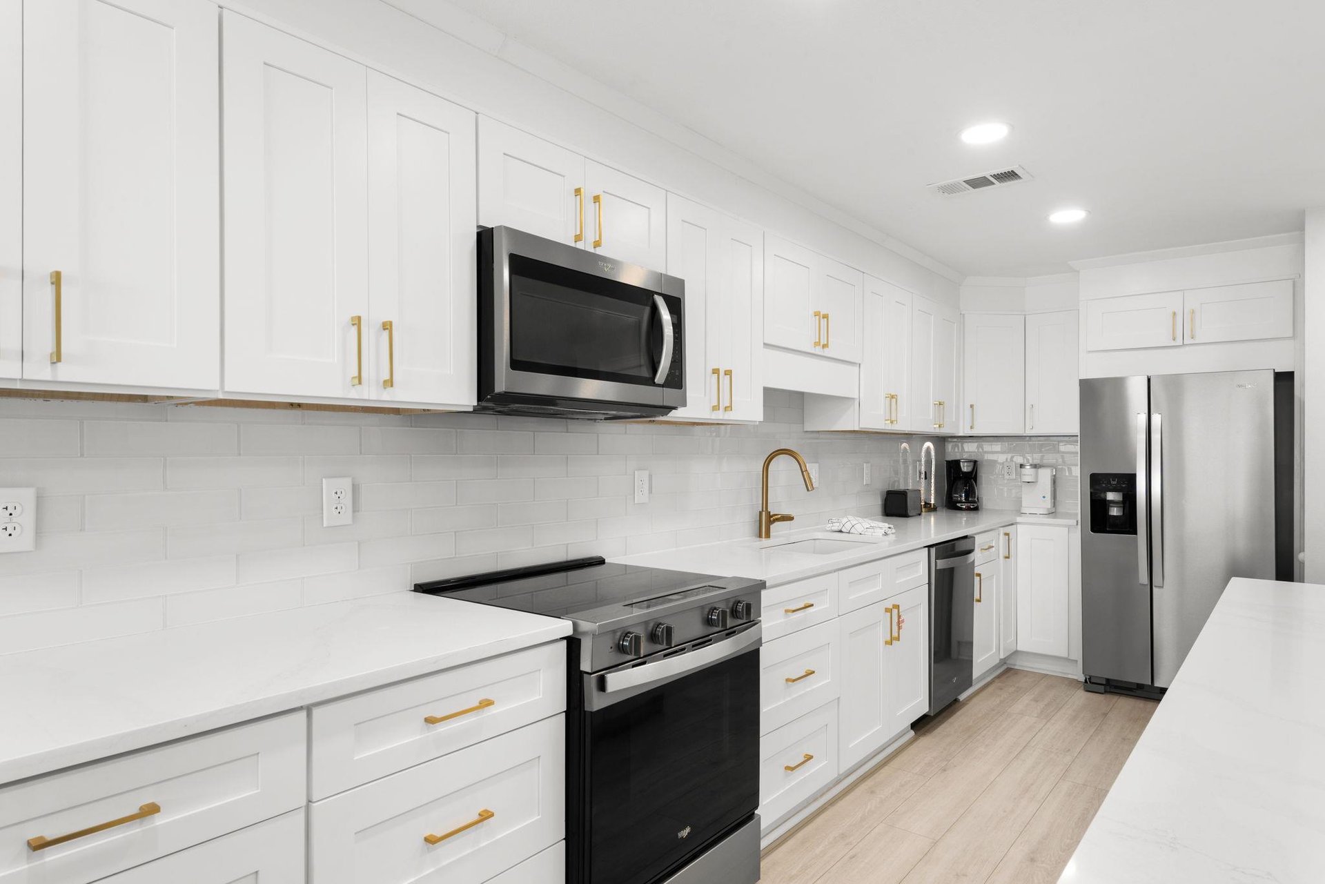 Your bright, modern kitchen awaits with sleek white cabinetry, gold fixtures, and stainless steel appliances—perfect for whipping up meals while you enjoy your getaway.