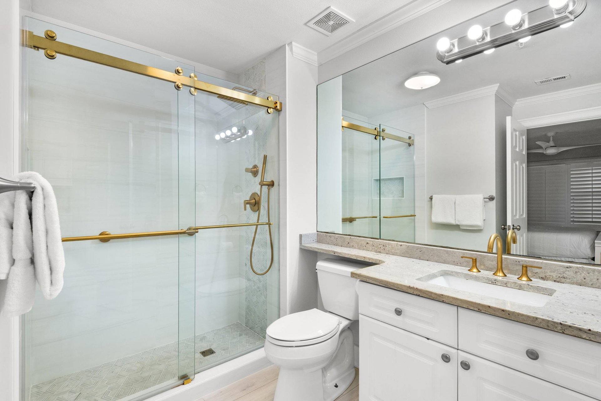 Your modern bathroom features elegant gold fixtures, a spacious walkin shower, and a beautifully lit vanity—the perfect place to refresh after a day of exploring.