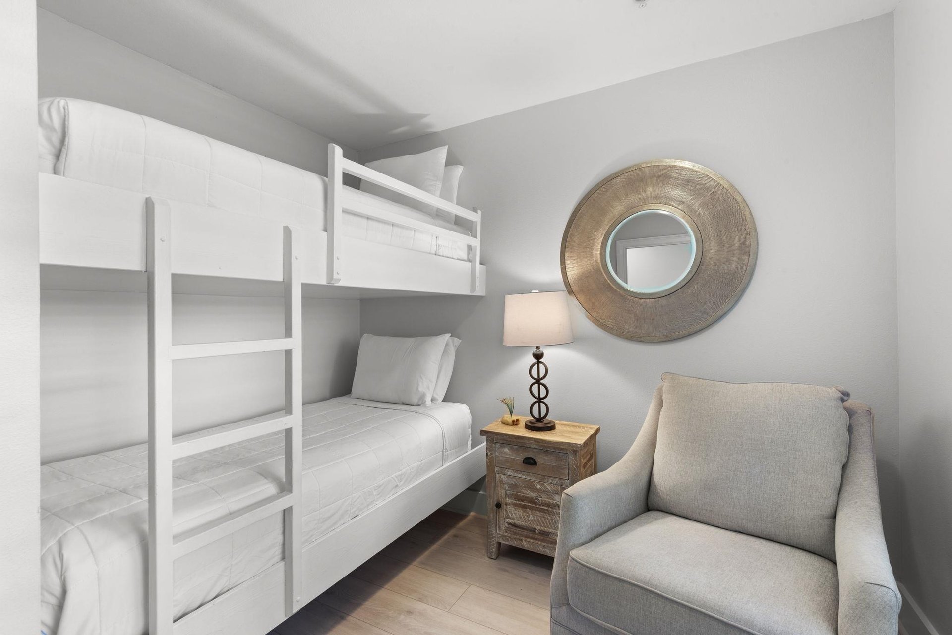 Youll find cozy sleeping arrangements with this spacesaving bunk bed setup, thoughtfully designed with crisp white linens and a comfortable chair for unwinding after your days adventures.