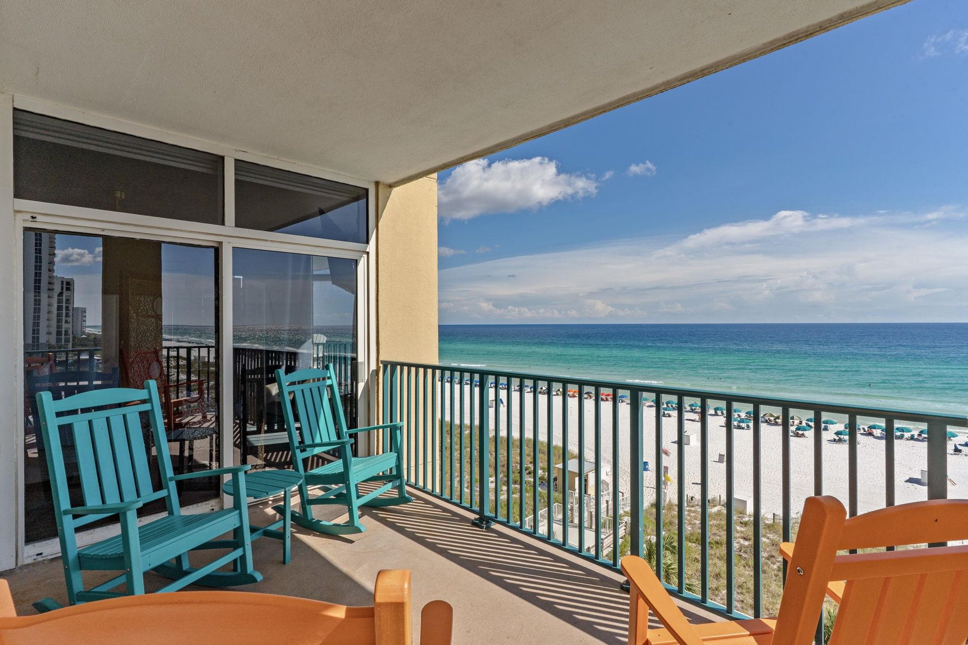 Settle into your private balcony where brilliant turquoise waters and soft white sands stretch endlessly before you, inviting peaceful mornings in colorful rocking chairs.