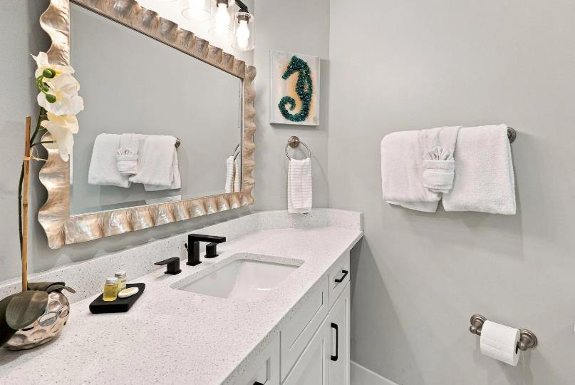 Primary Bathroom  Your private bathroom feels fresh and coastal, with soft white linens, a shellframed mirror, and subtle seaside touches that add charm to your daily routine.