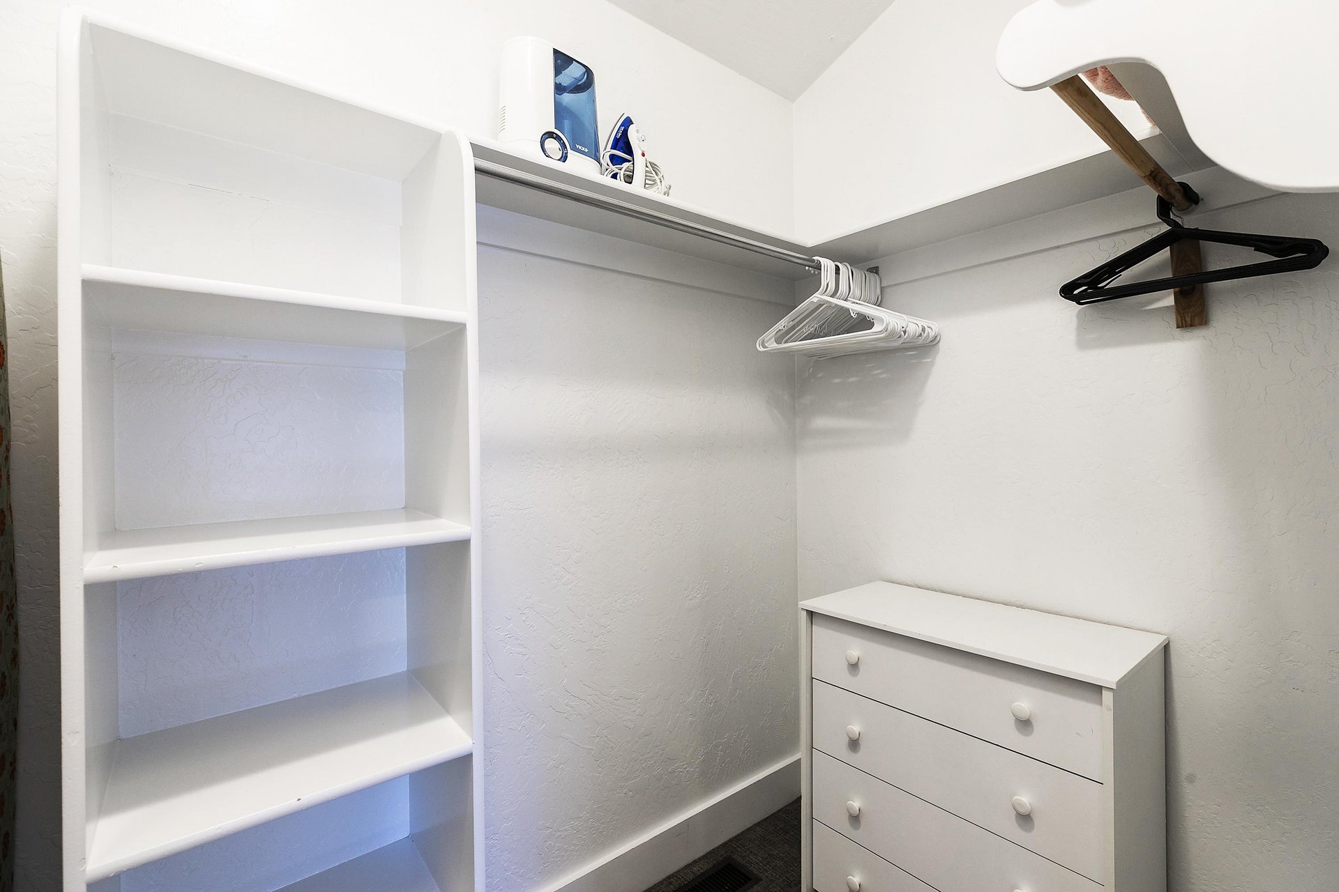 Spacious walkin closet in the main bedroom with built in cubbies, dresser, and racks