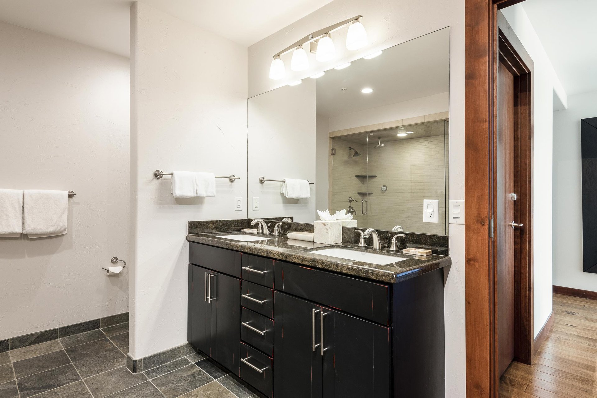 Main ensuite bathroom, dual vanity granite countertops with dark wood drawers and large frameless mirror