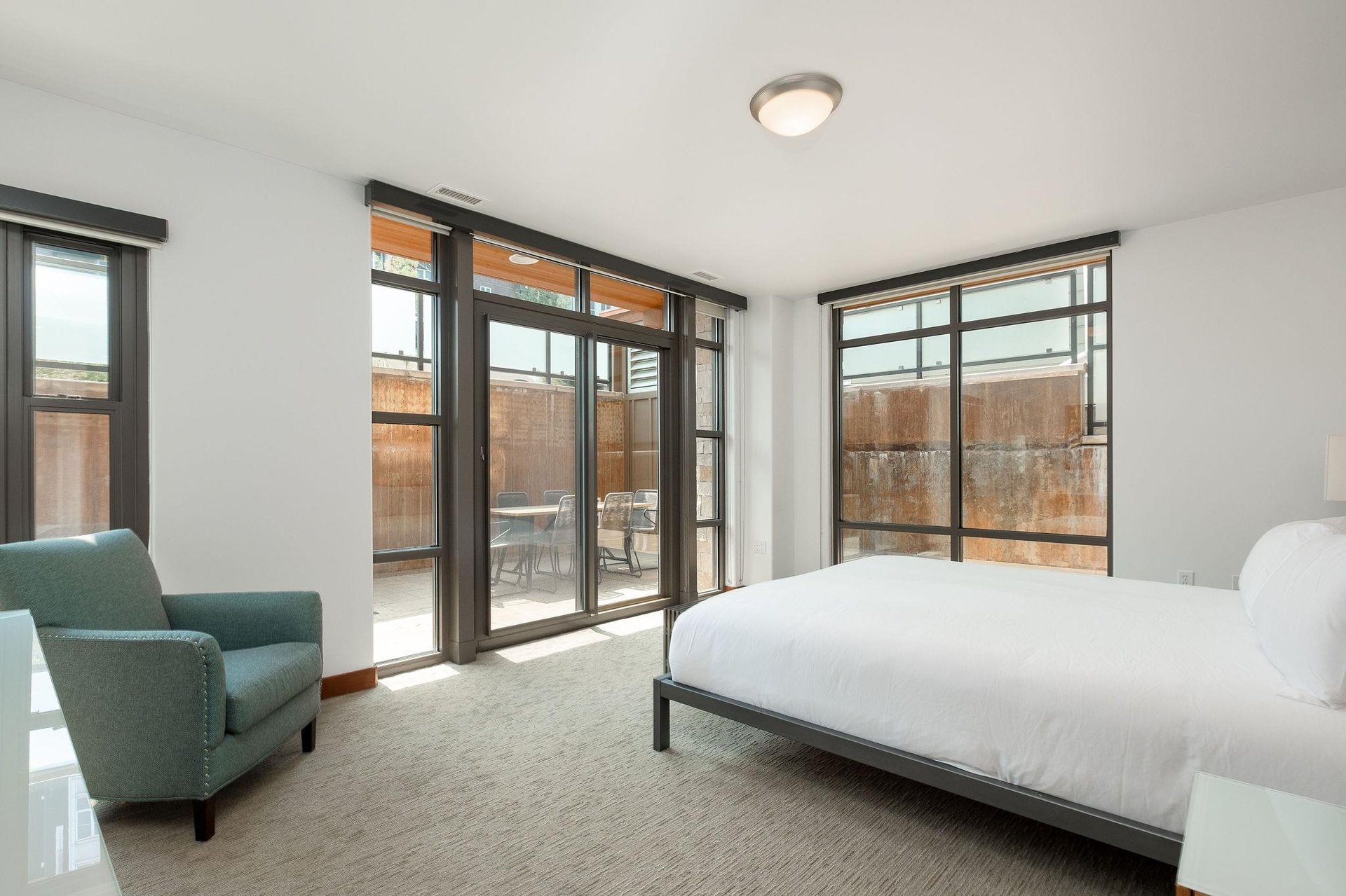 Access the private patio off the main bedroom with sliding glass doors, large window walls flank the bedroom flooding with natural light, and convenient lounge chair
