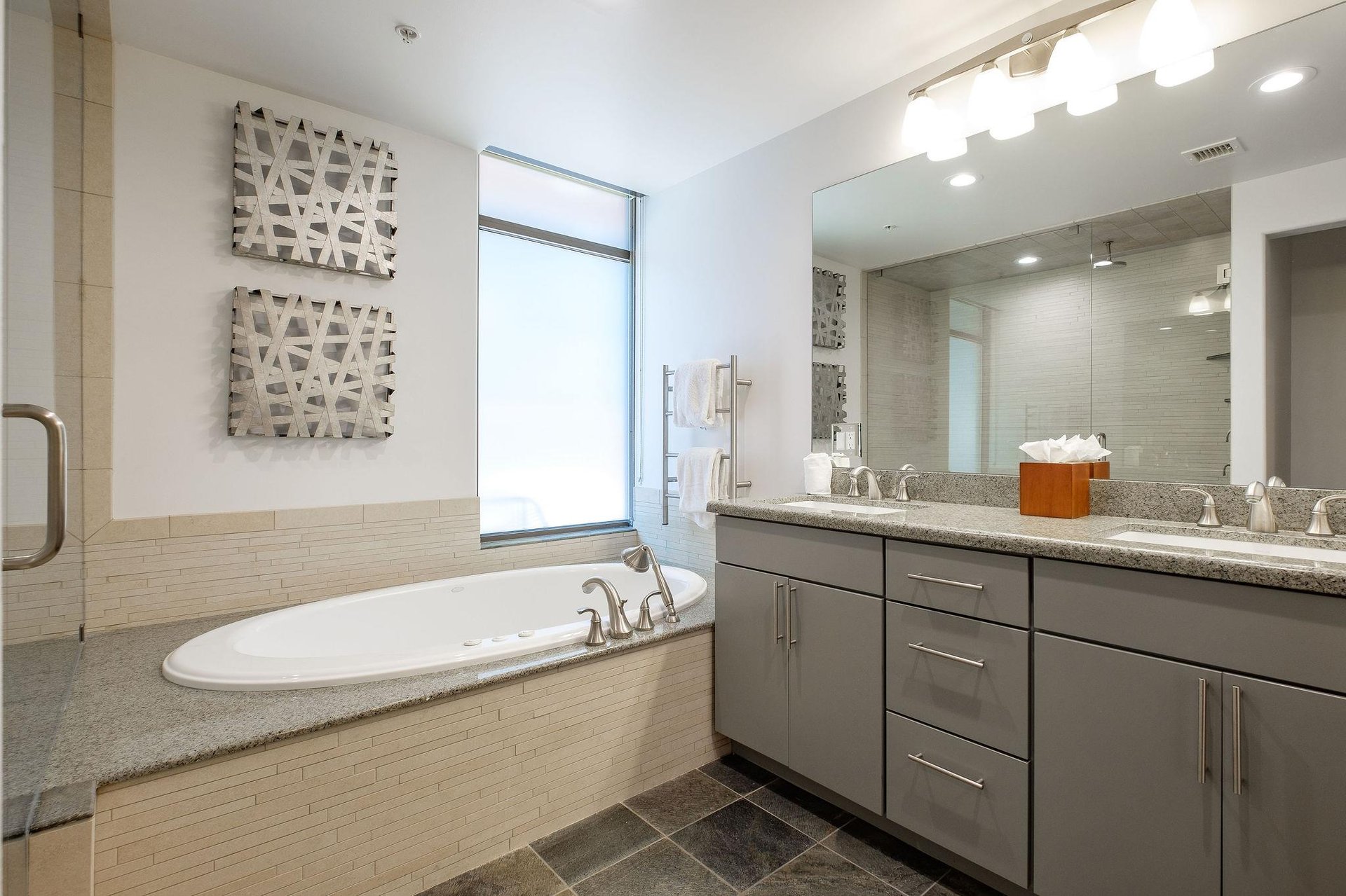 Full ensuite main bathroom with double vanity, granite countertops, and soaking jetted tub