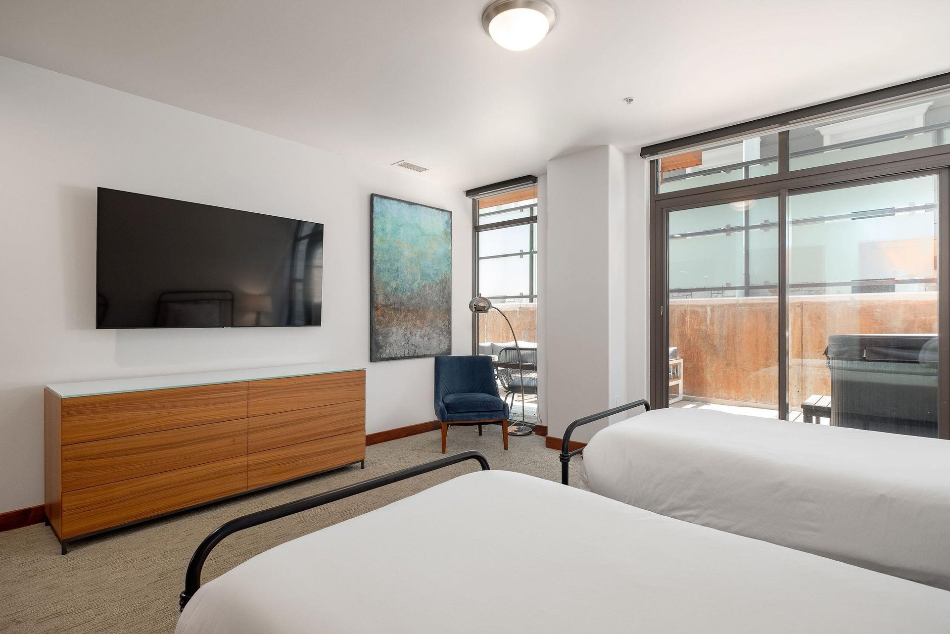 Guest bedroom with dedicated patio access via sliding glass doors, large flat screen wall mounted TV over double wooden dresser