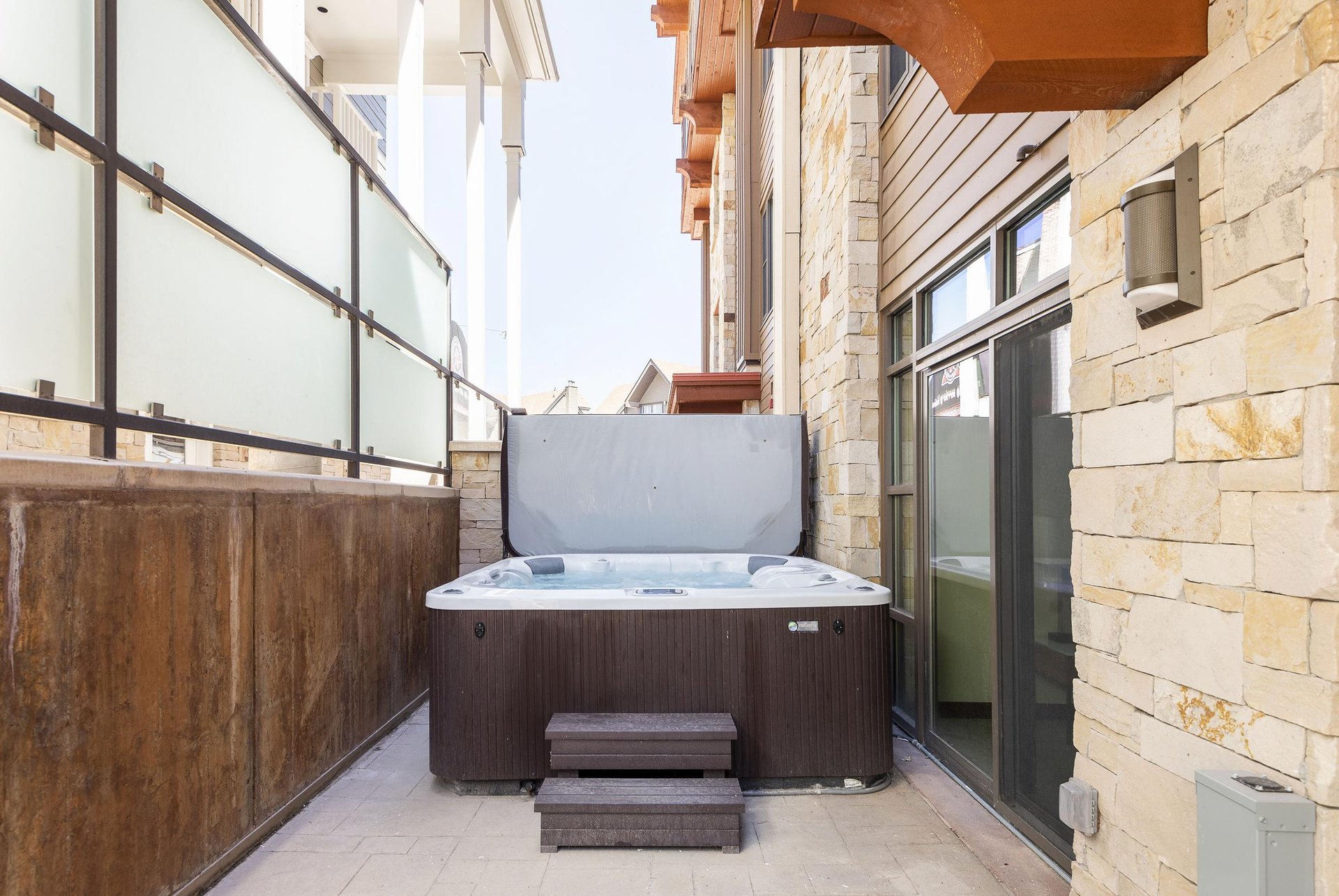 Private jetted hot tub on the patio with privacy panels along the resort plaza