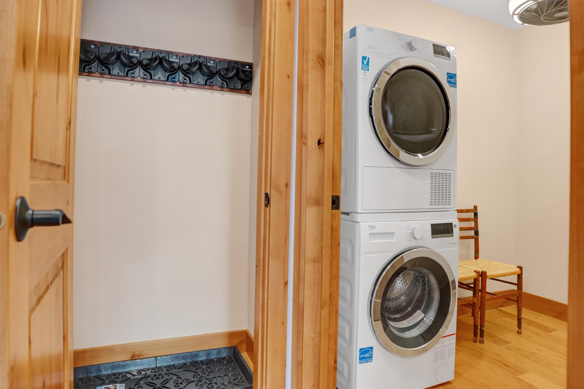 Private stacked washer dryer and ski closet with racks at entryway