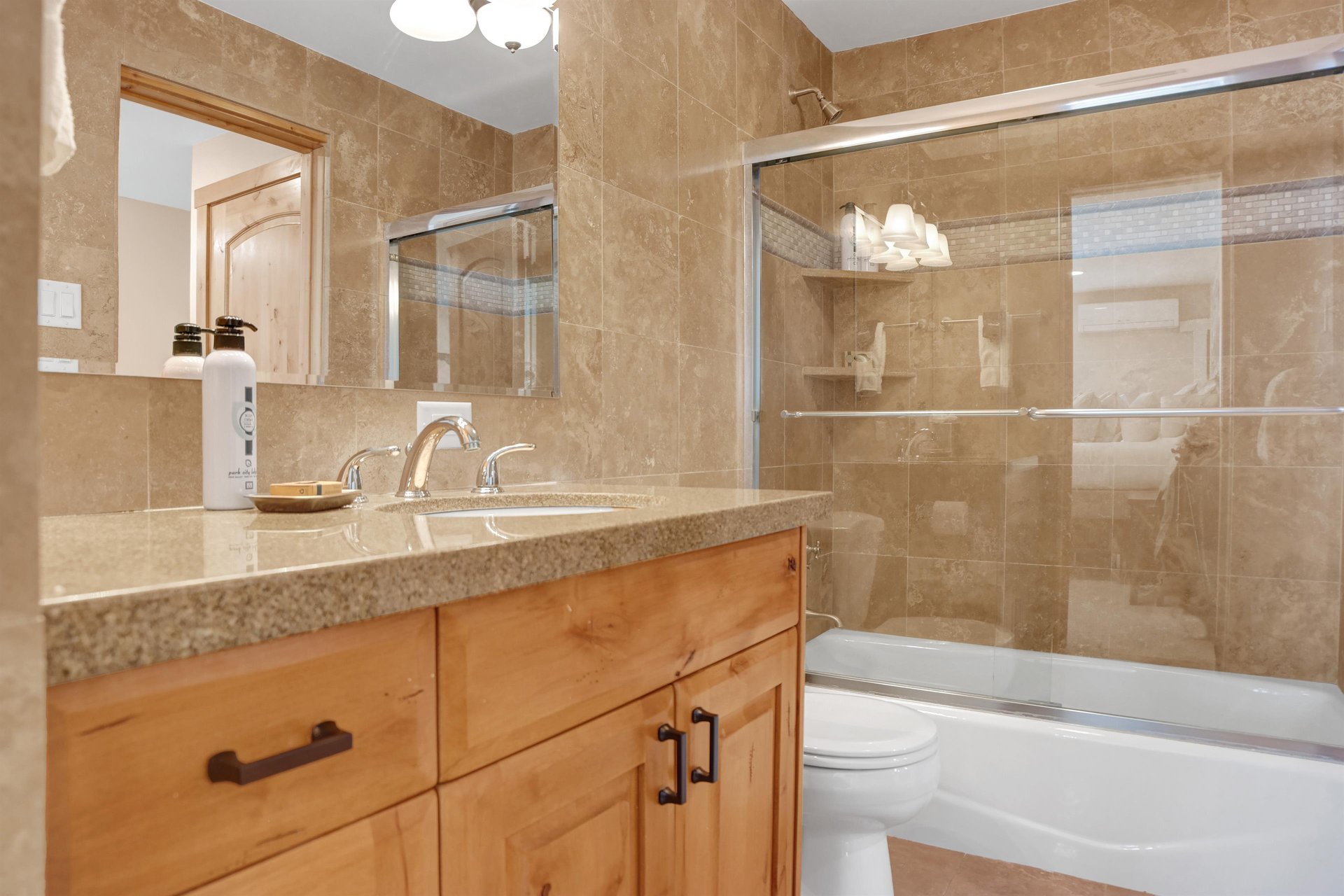 Full bathroom with granite countertops, tiled walls, glass sliding shower door