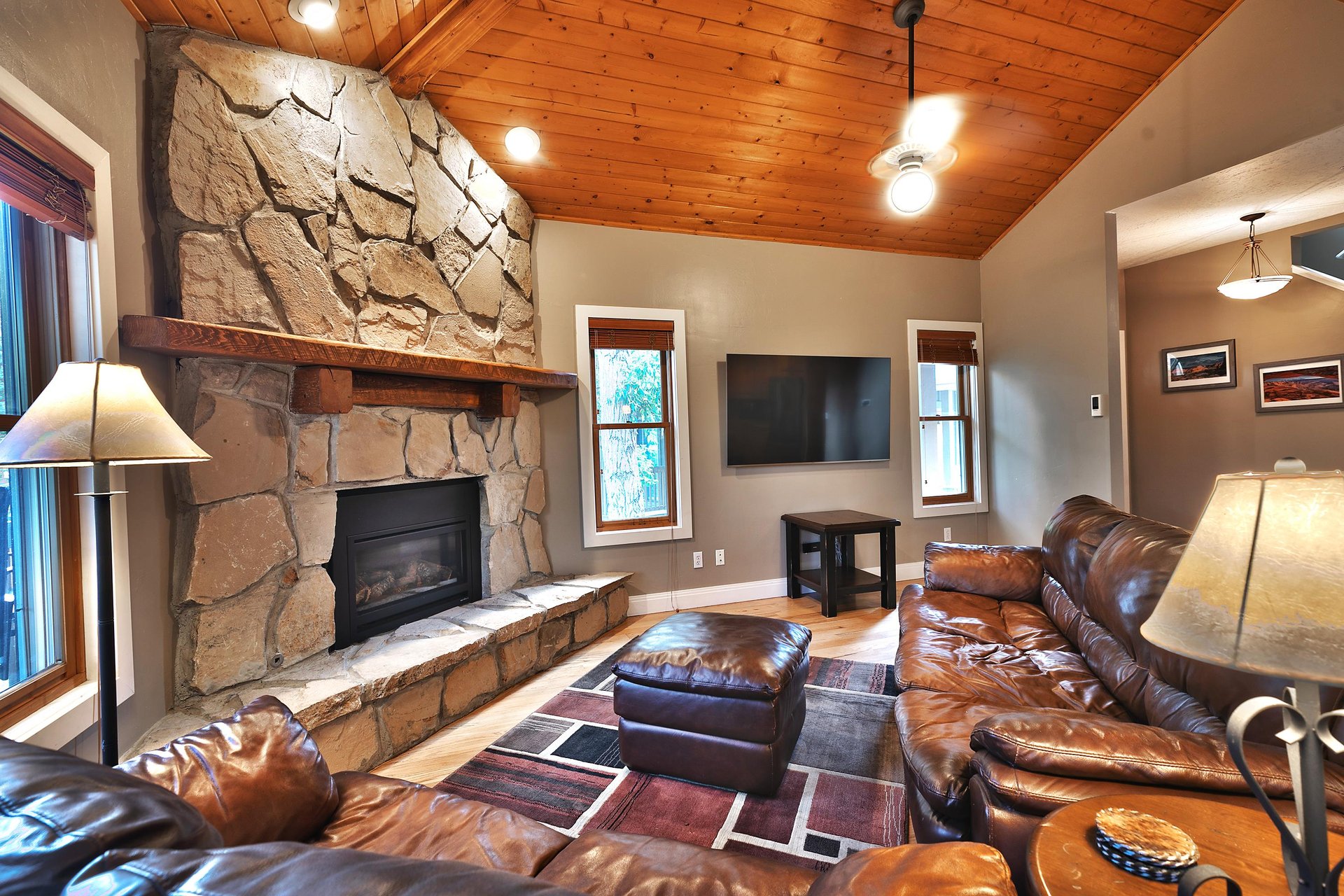 Living room with feature rock fireplace wall, leather couches and wall mounted flat screen TV
