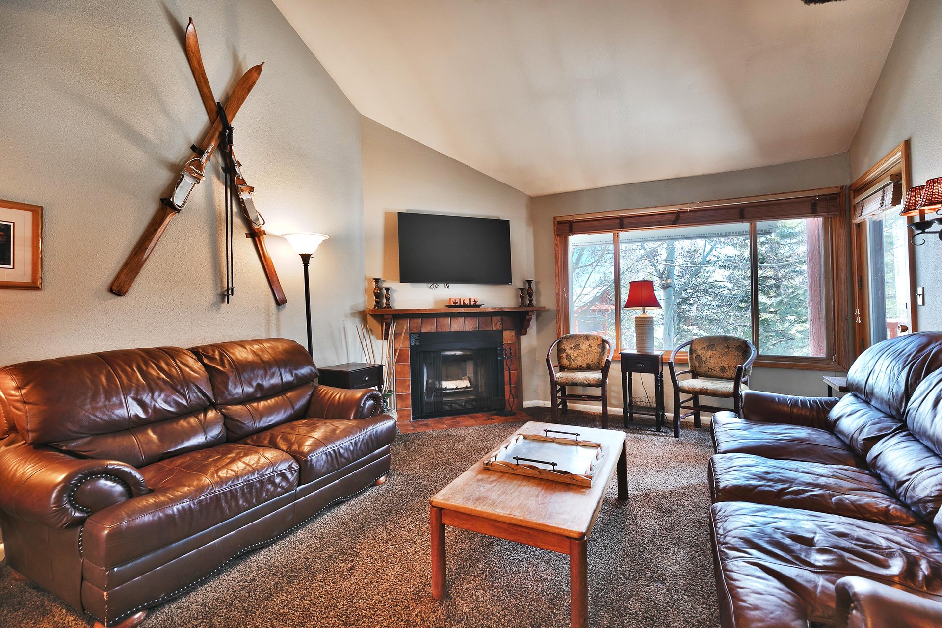 Living room has a wall mounted flat screen tv above the tiled surround wood burning fireplace