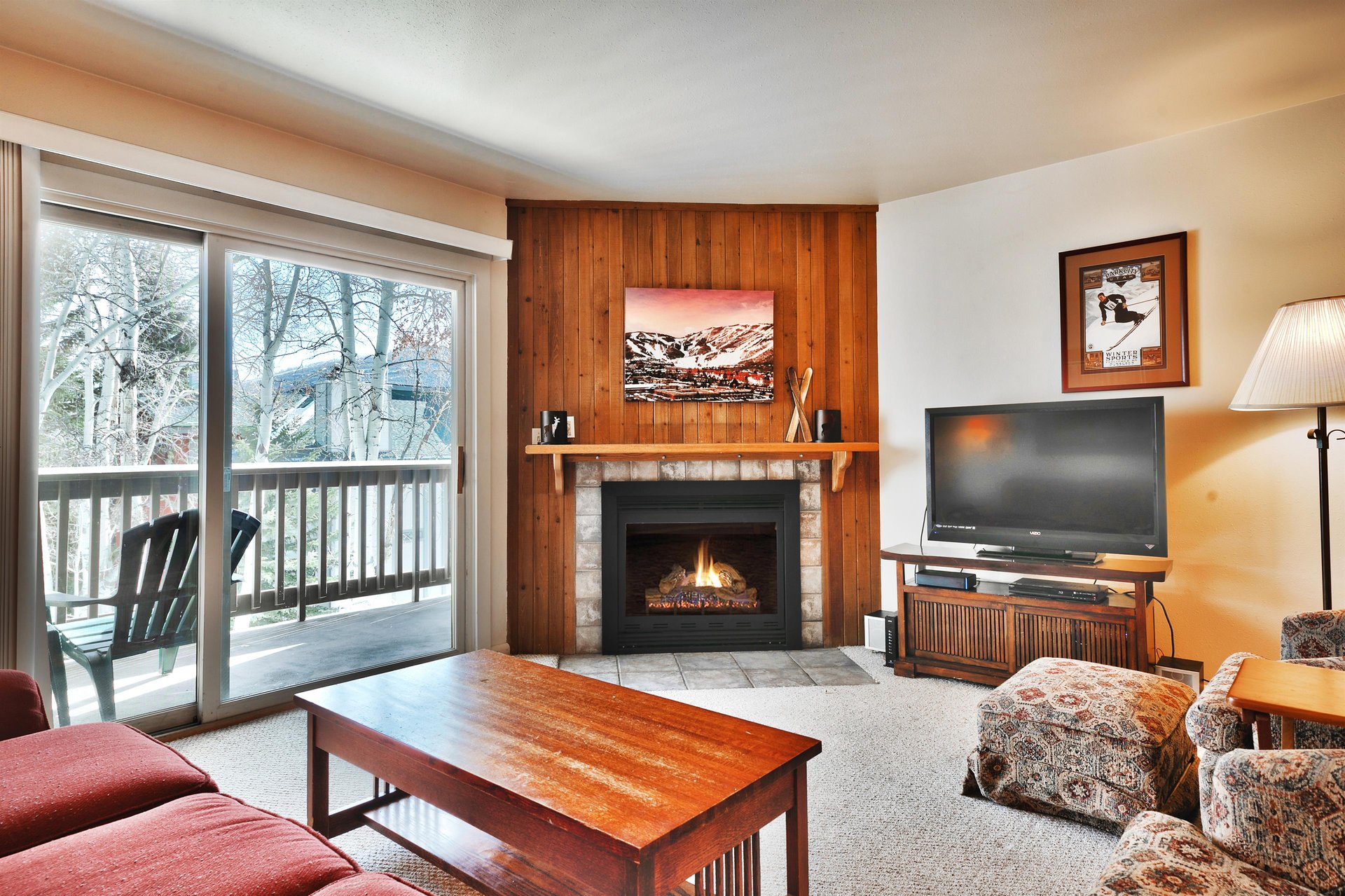 Living room with gas fireplace has wood paneling and tile surround to relax around after a day of skiing.