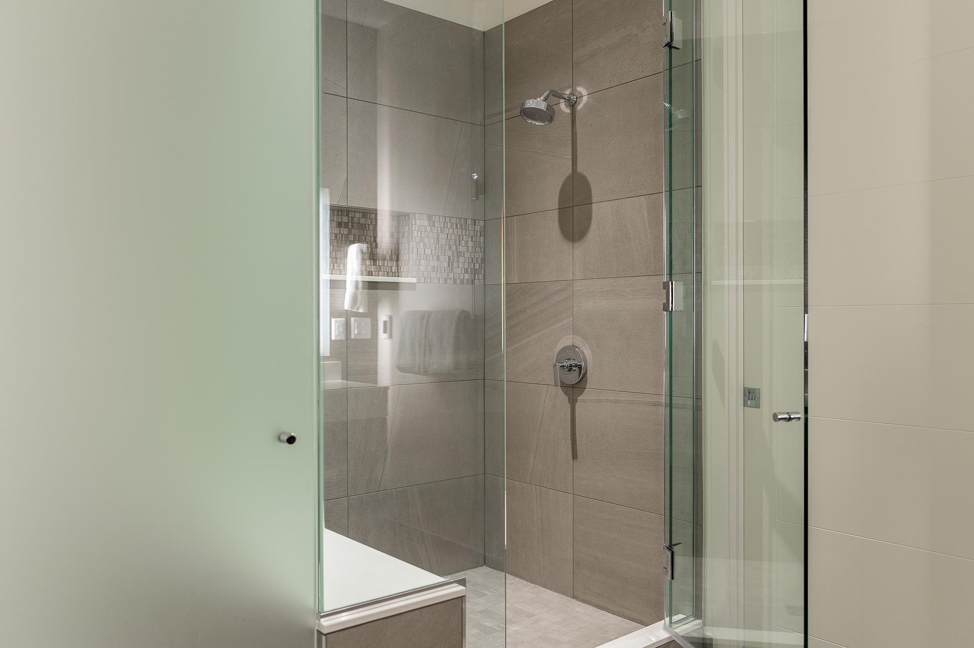Tiled shower in the main bathroom with glass panel doors and chrome fixtures