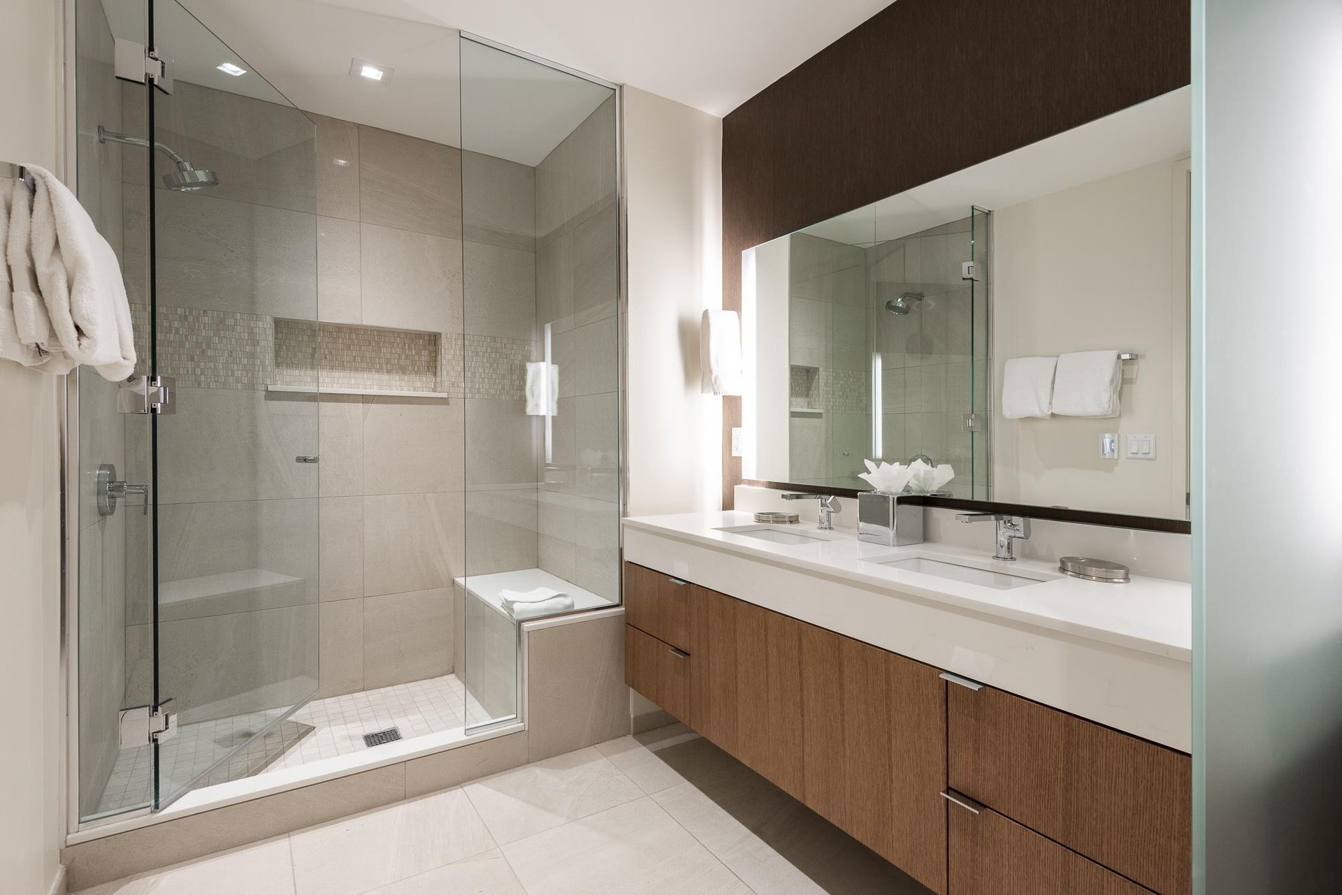 Ensuite main bath with two vanities, glass paneled shower door and tiled shower with bench