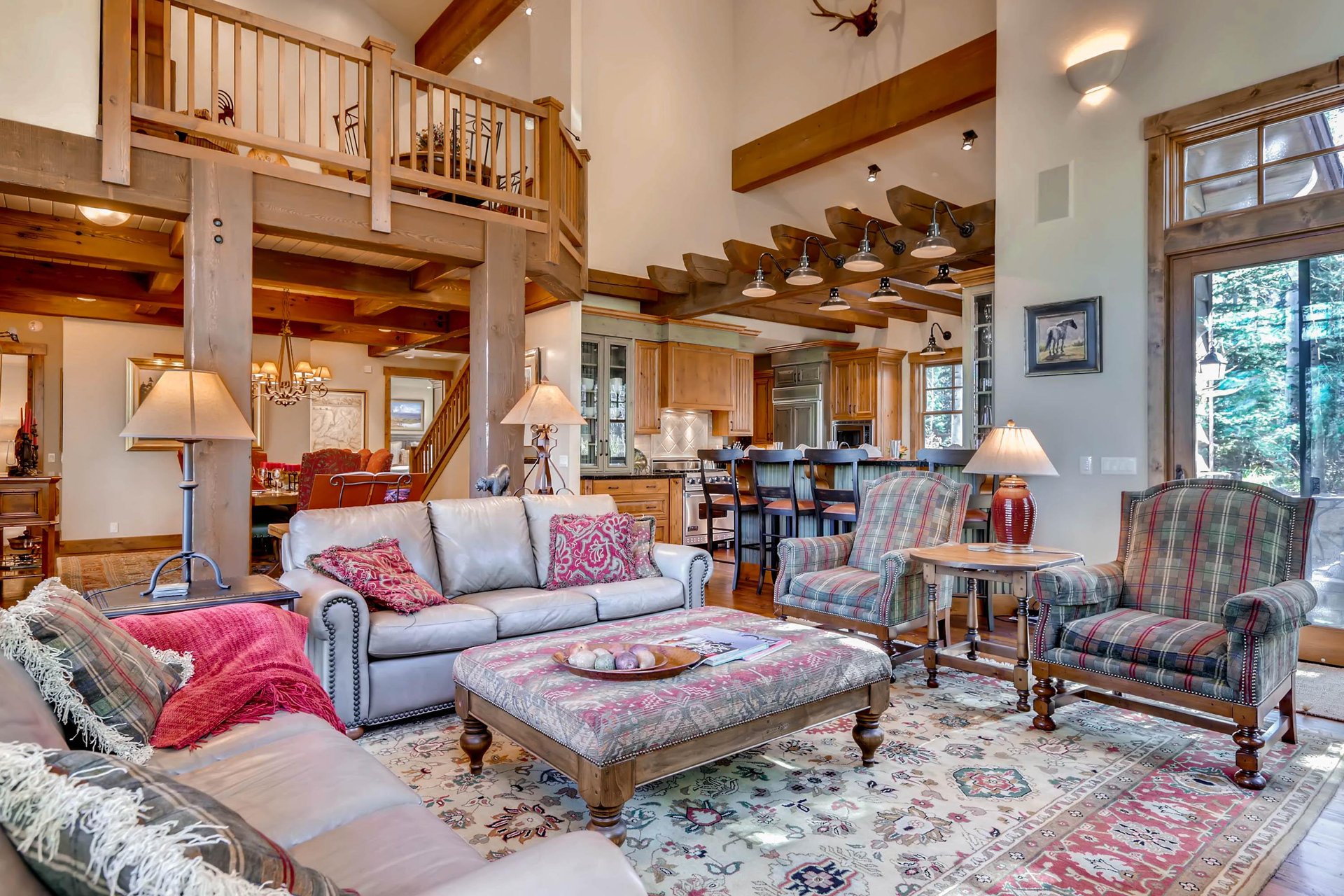 Welcoming open floor plan with high vaulted ceilings, hardwood floors, ornate area rugs, complete with two leather couches in the living room and two large armcharis