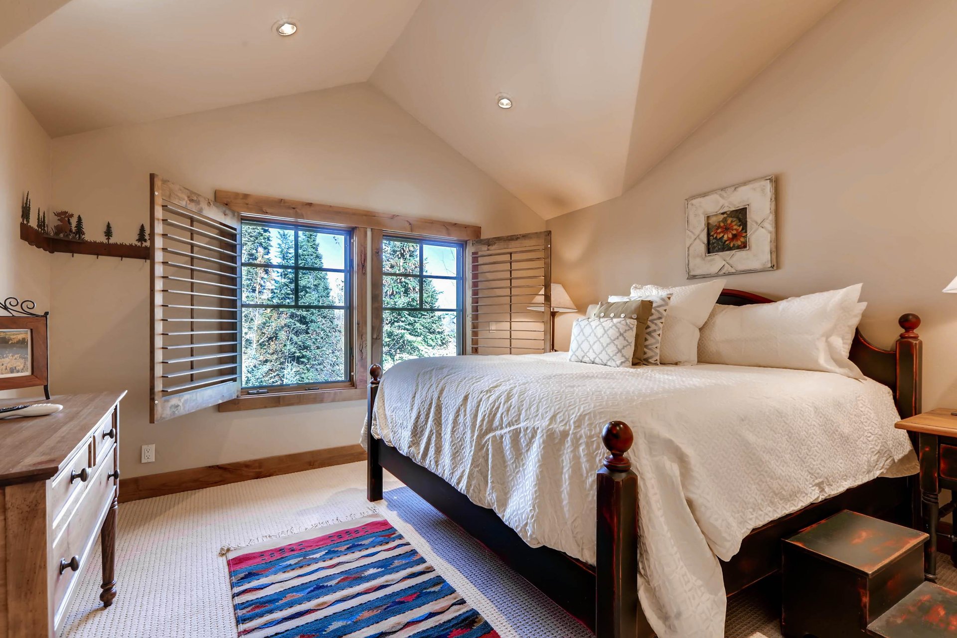 Graceful king bed in the third guest bedroom, wooden bedframe and large picture windows with wooden blinds