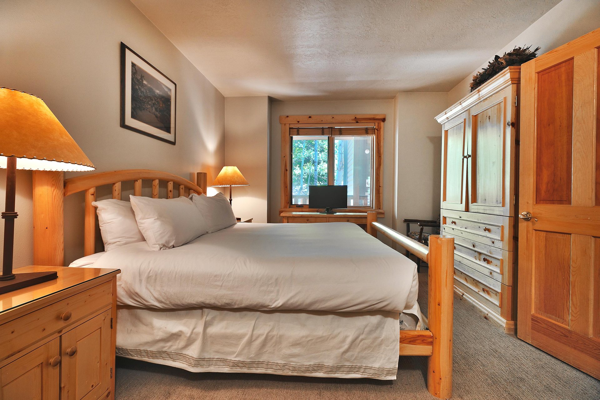 First king bedroom with large wooden armoire, flat screen TV and window with mountainside views