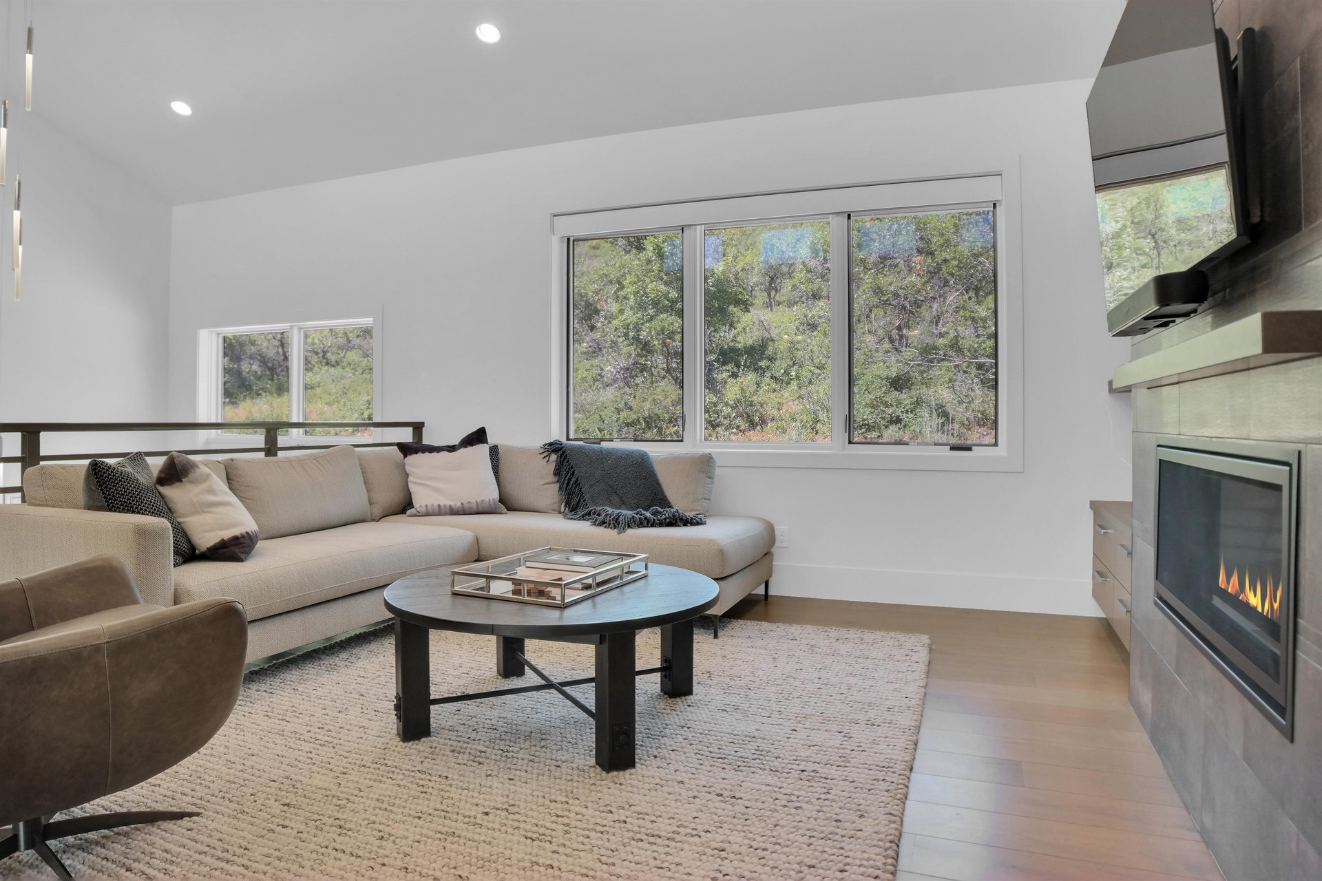 Vacation rental second living room with light grey sectional sofa and views of the surrounding hillside of oak trees.