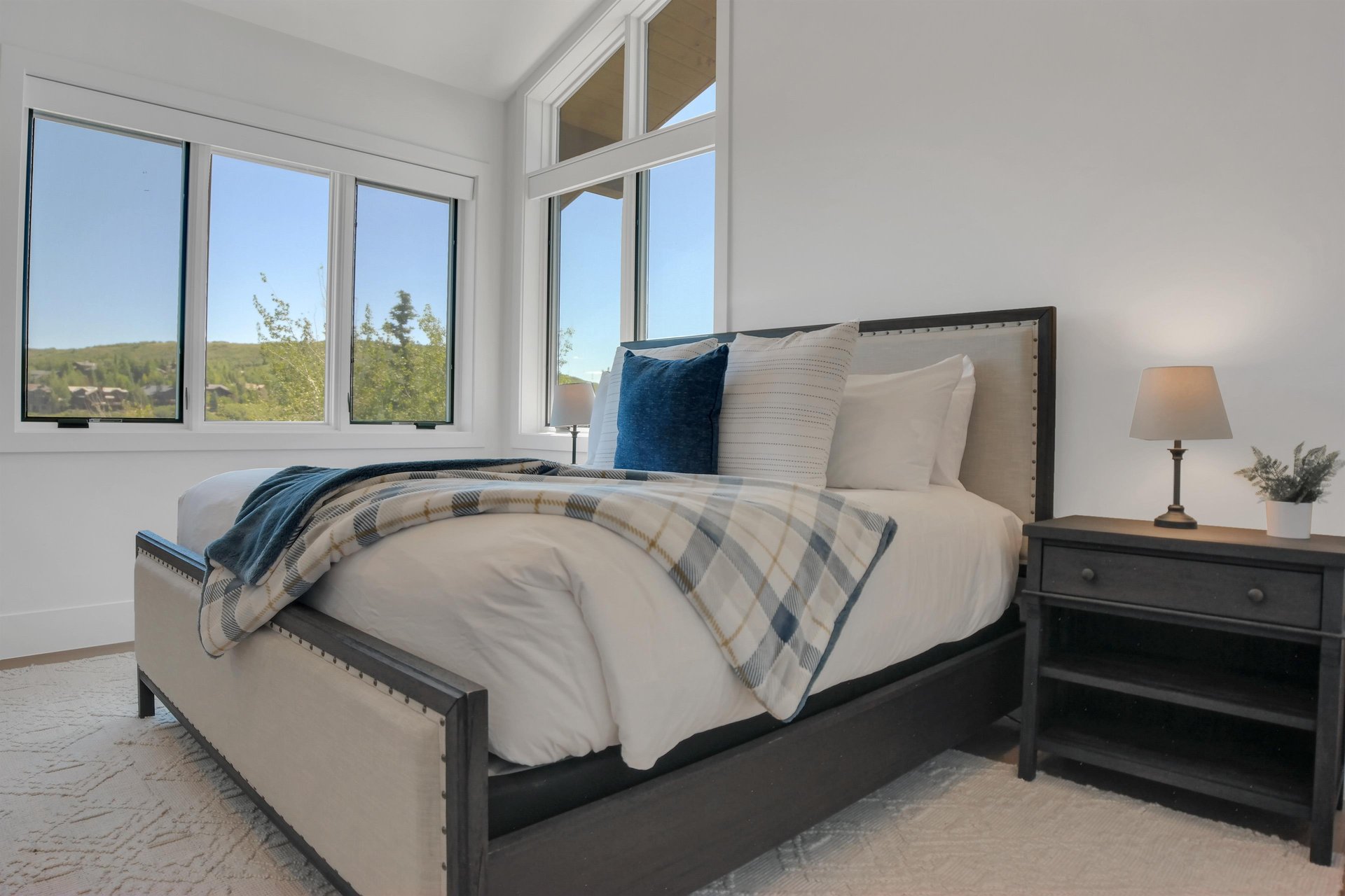 Vacation rental bedroom with a king size bed and upholstered and wood bed frame with crisp white linens and blue accent pillows.