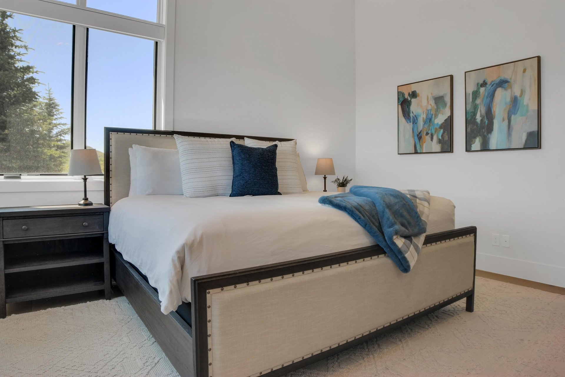 Vacation rental bedroom with a king size bed, solid wood end tables and modern art.