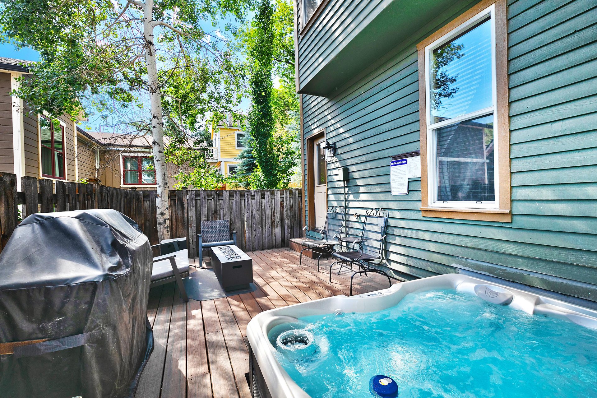 Secluded private back patio with bubbling hot tub, gas grill, and patio furniture set with gas firepit