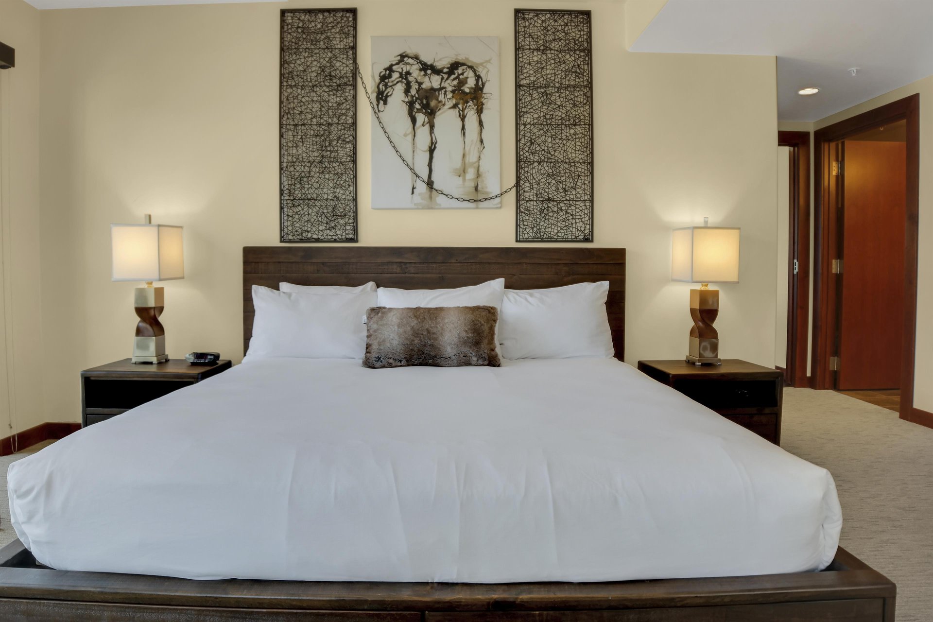Lowell 304s main suite with king size bed, two nights stands with lamps and horse painting above the bed.