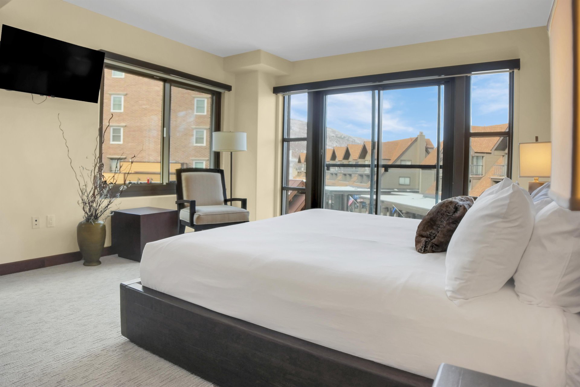 Lowell 304s main suite with king size bed, large picture windows, and chair with floor lamp.