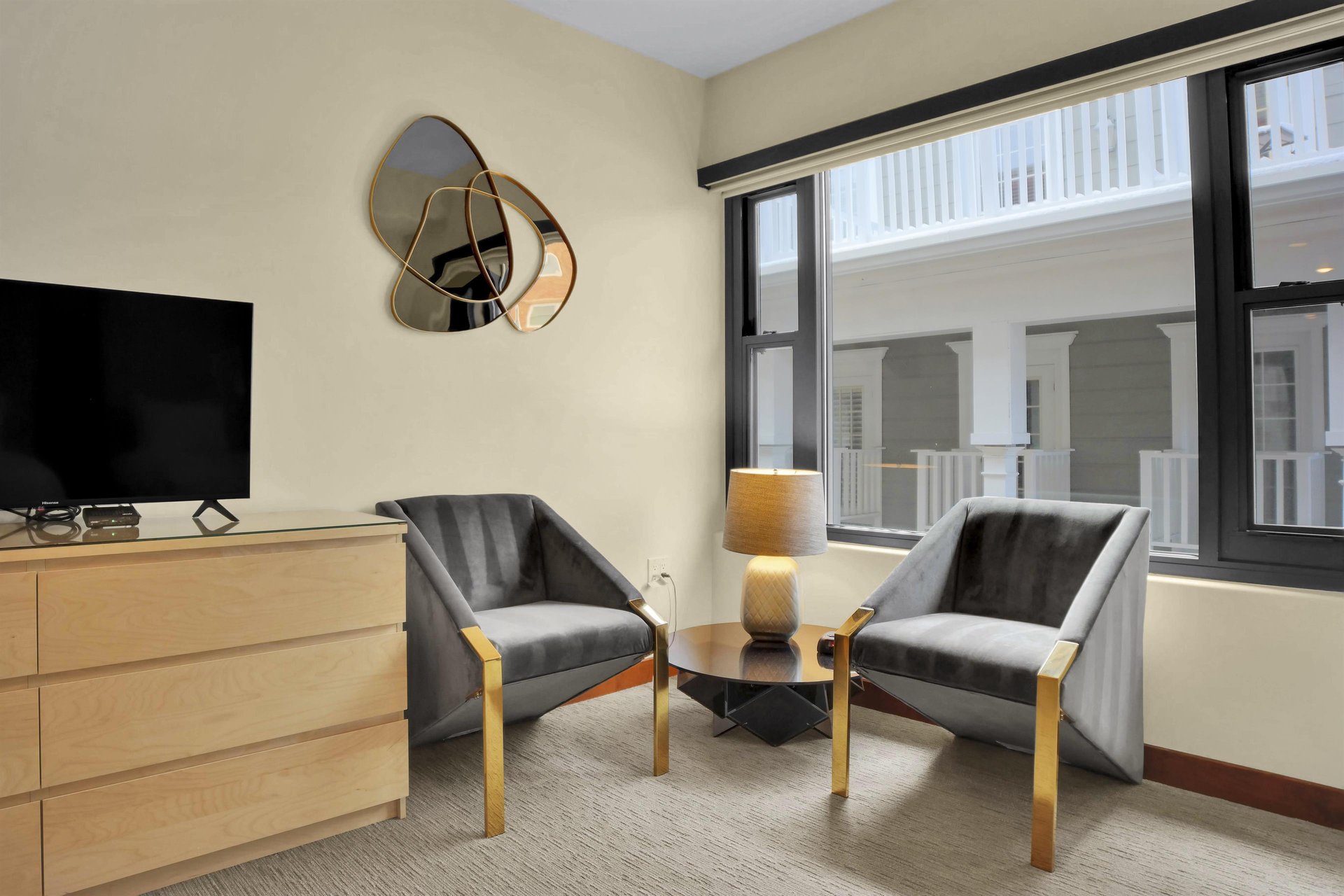The second bedroom has two chairs, side table with a lamp, and wooden dresser.