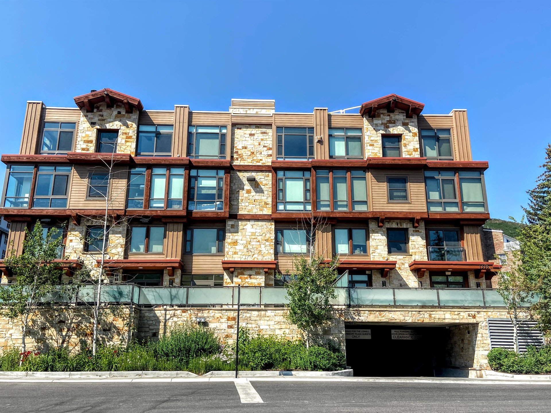 The Lowell building with stone wall around the front and a 4 story building with a parking garage entrance.
