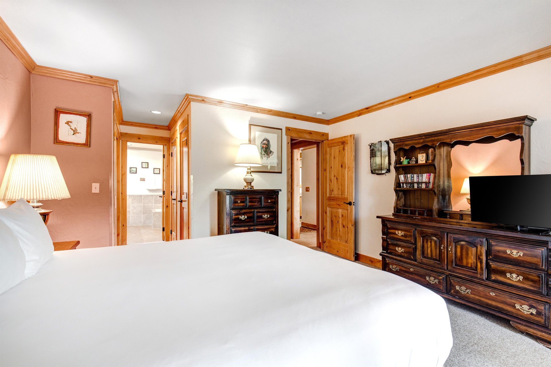 Snow Flowers 43s main suite has a kingsize bed, with white linens, dark wood furniture and light wood trim around the room.