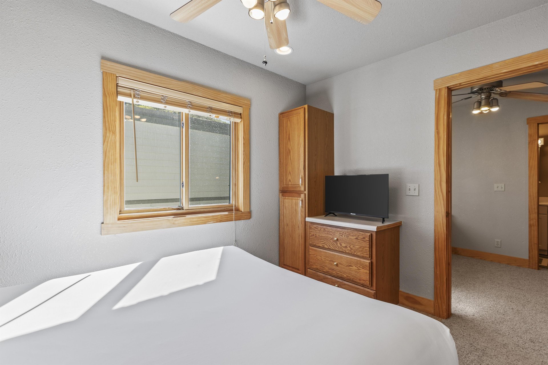 Snow Flower 72s bedroom with queen bed, wooden dresser, and ceiling fan.