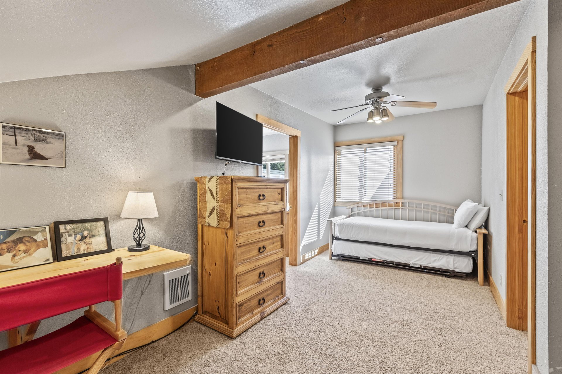 Snow Flower 72s bedroom with a twin bed with twin trundle, and blonde wood dresser, flat screen TV, and desk table.