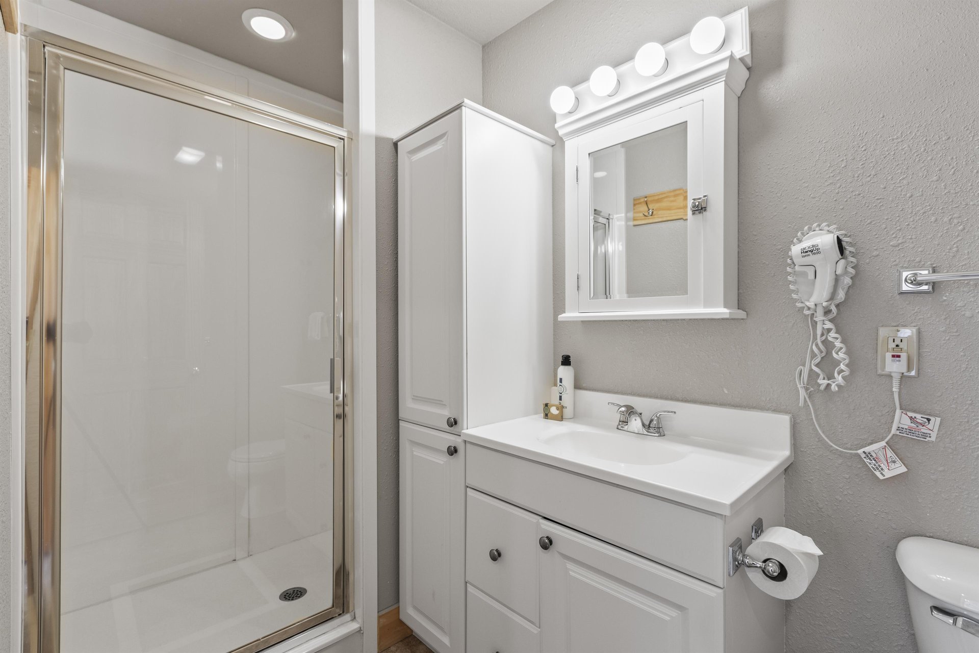 Snow Flower 72s bathroom with greige walls, white cabinets, and white walk in shower.