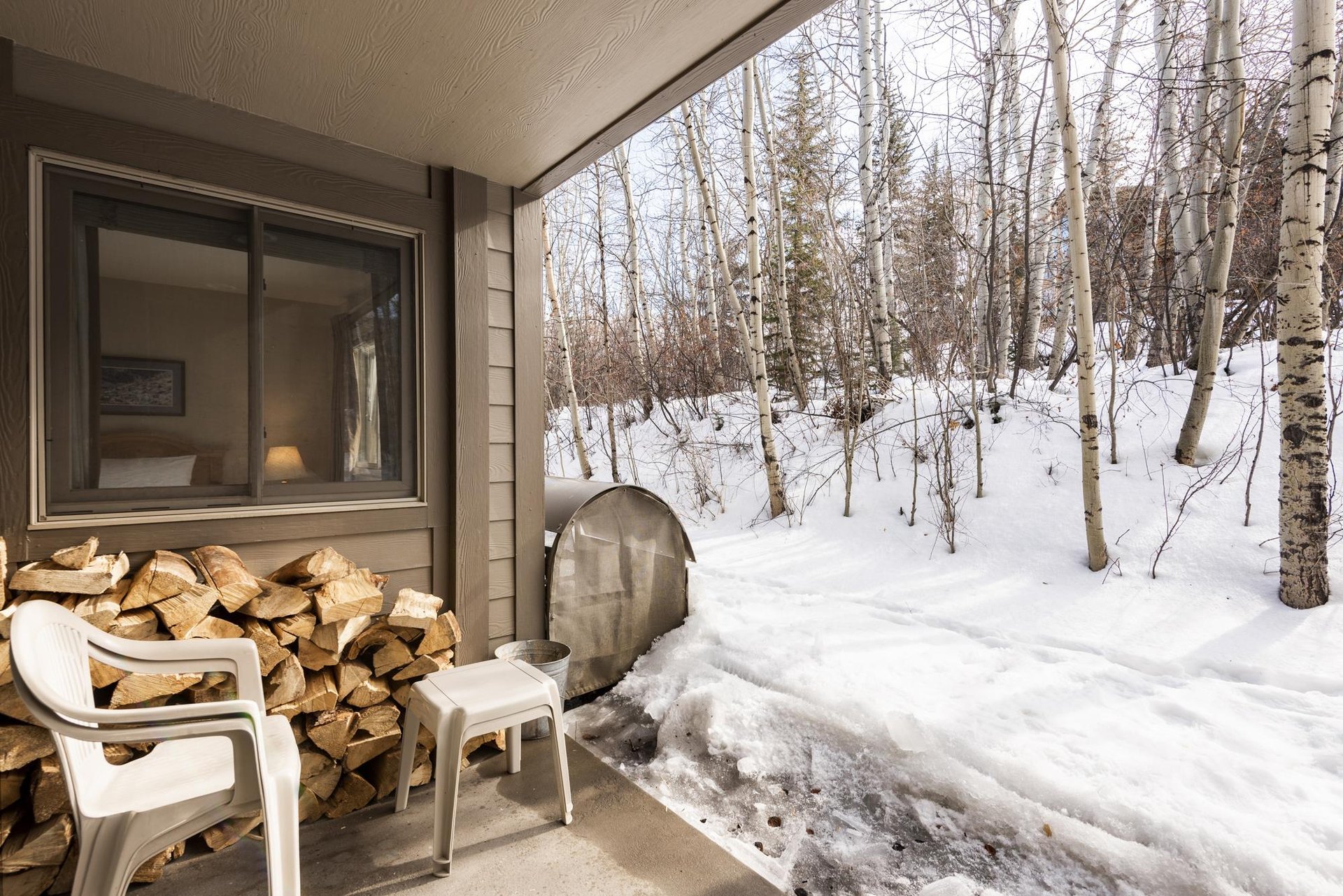 Relax on the private patio on white chairs next to freshly fallen snow and the aspen grove.
