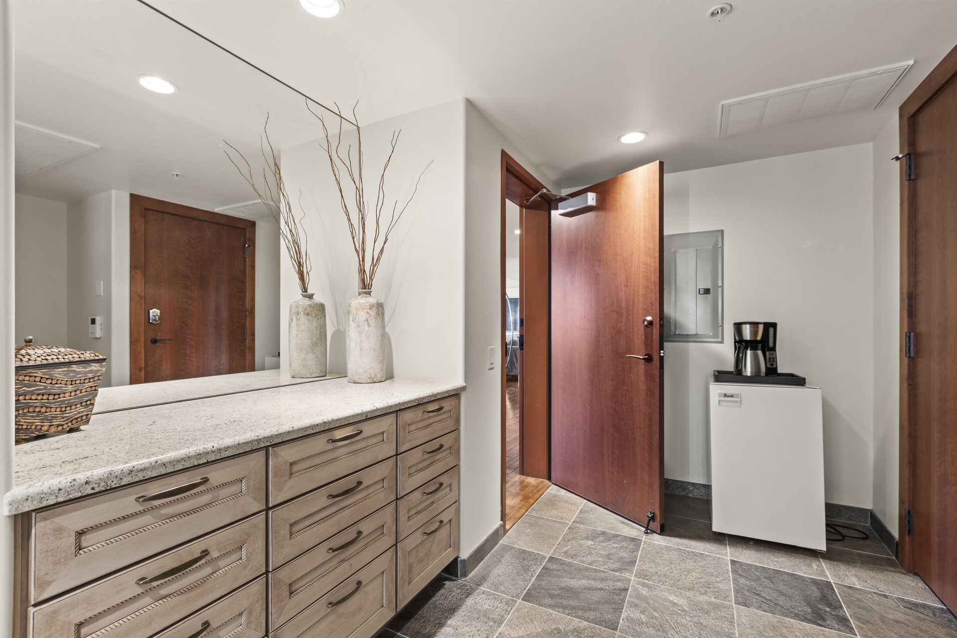 The entryway with built in cabinets, mini fridge and coffee pot.