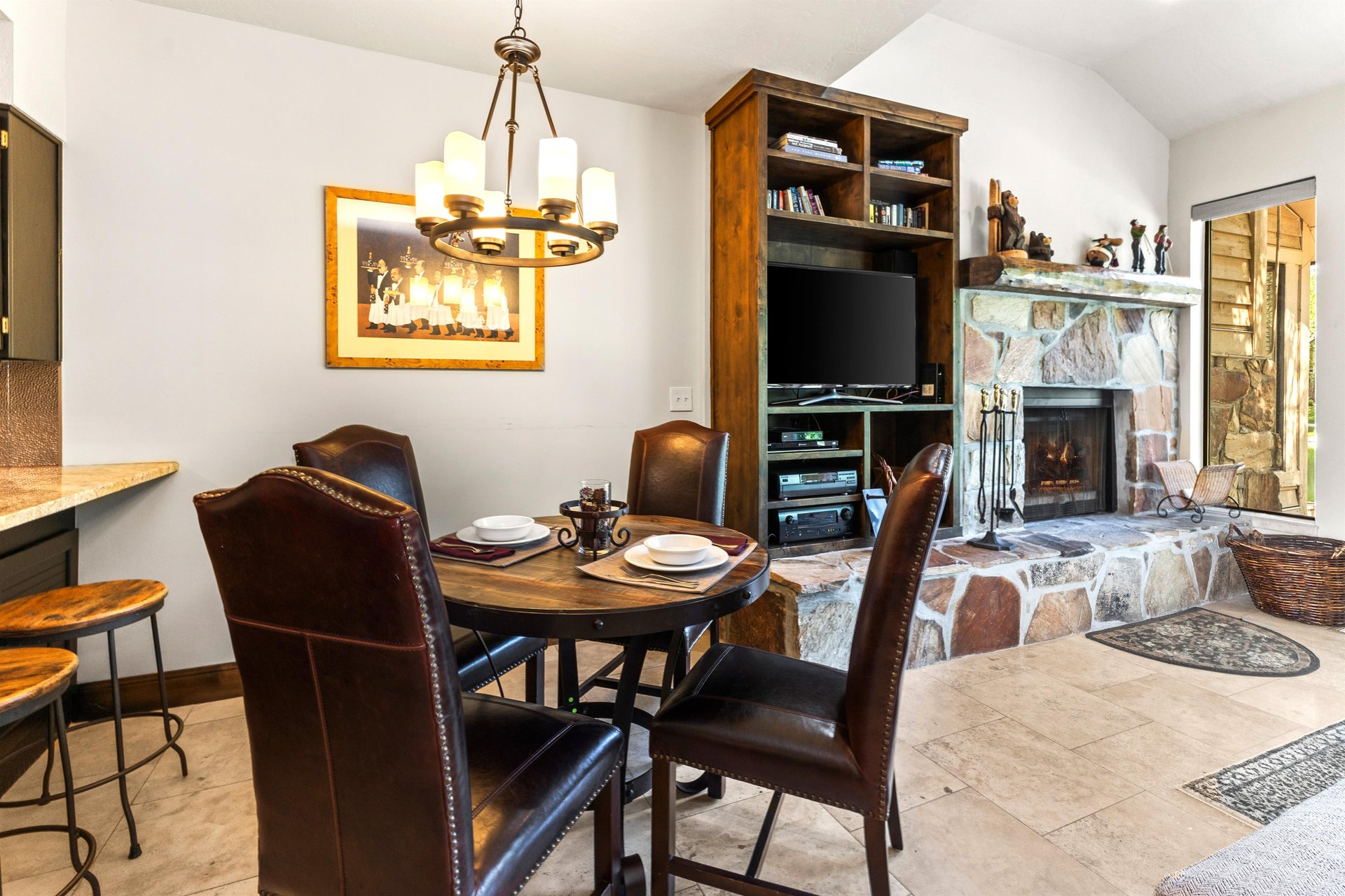 Queen Esther 2425s dining area with seating for 4 on leather chairs and a round table and art on the wall behind.