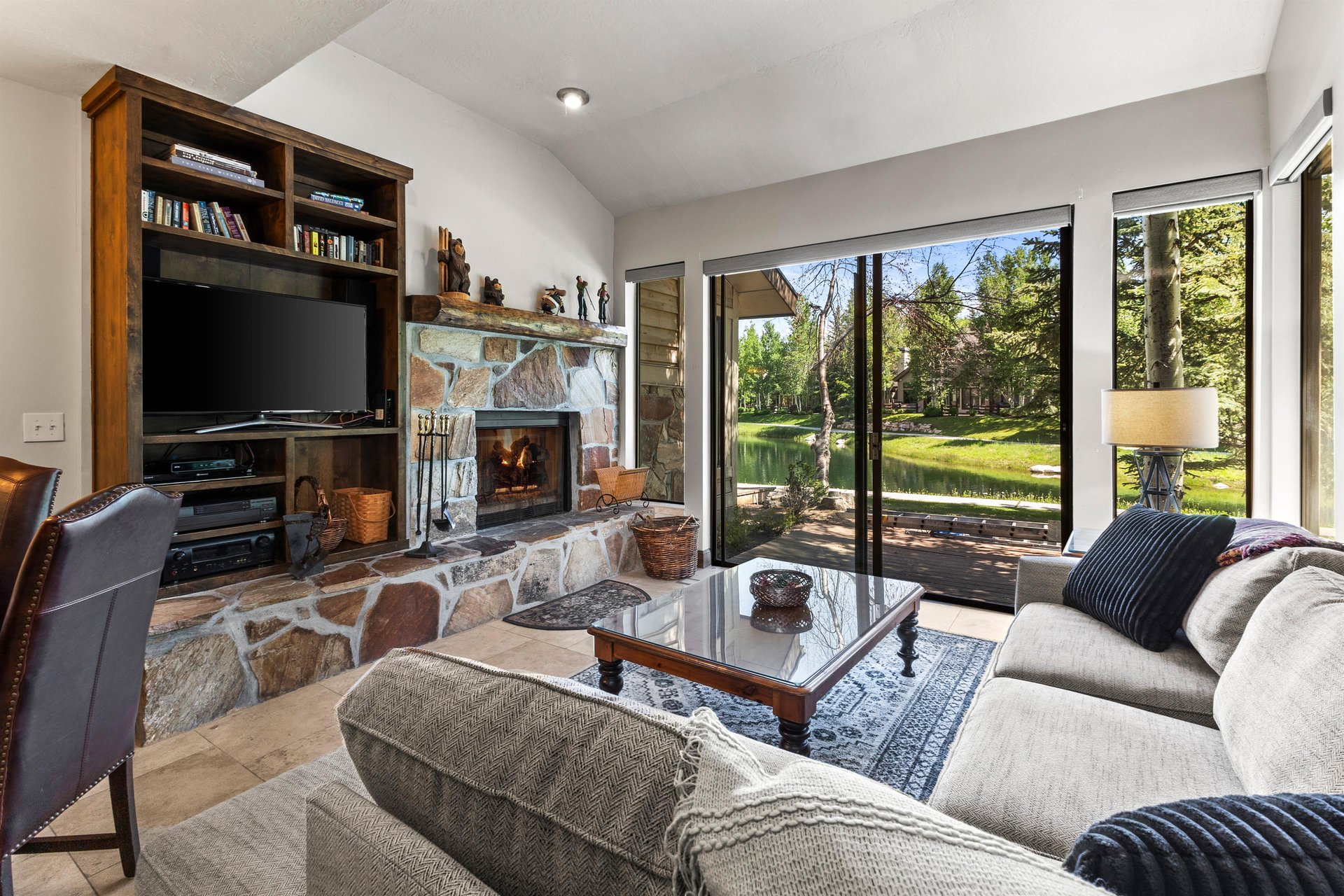 The living room has a builtin wood fireplace with stone surround and builtin cabinet with flatscreen TV.