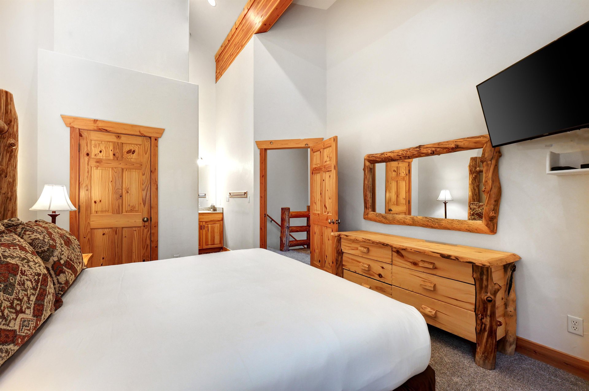 The main suite has a king size bed, wooden dresser, and vanity sink next to a separate water closet.