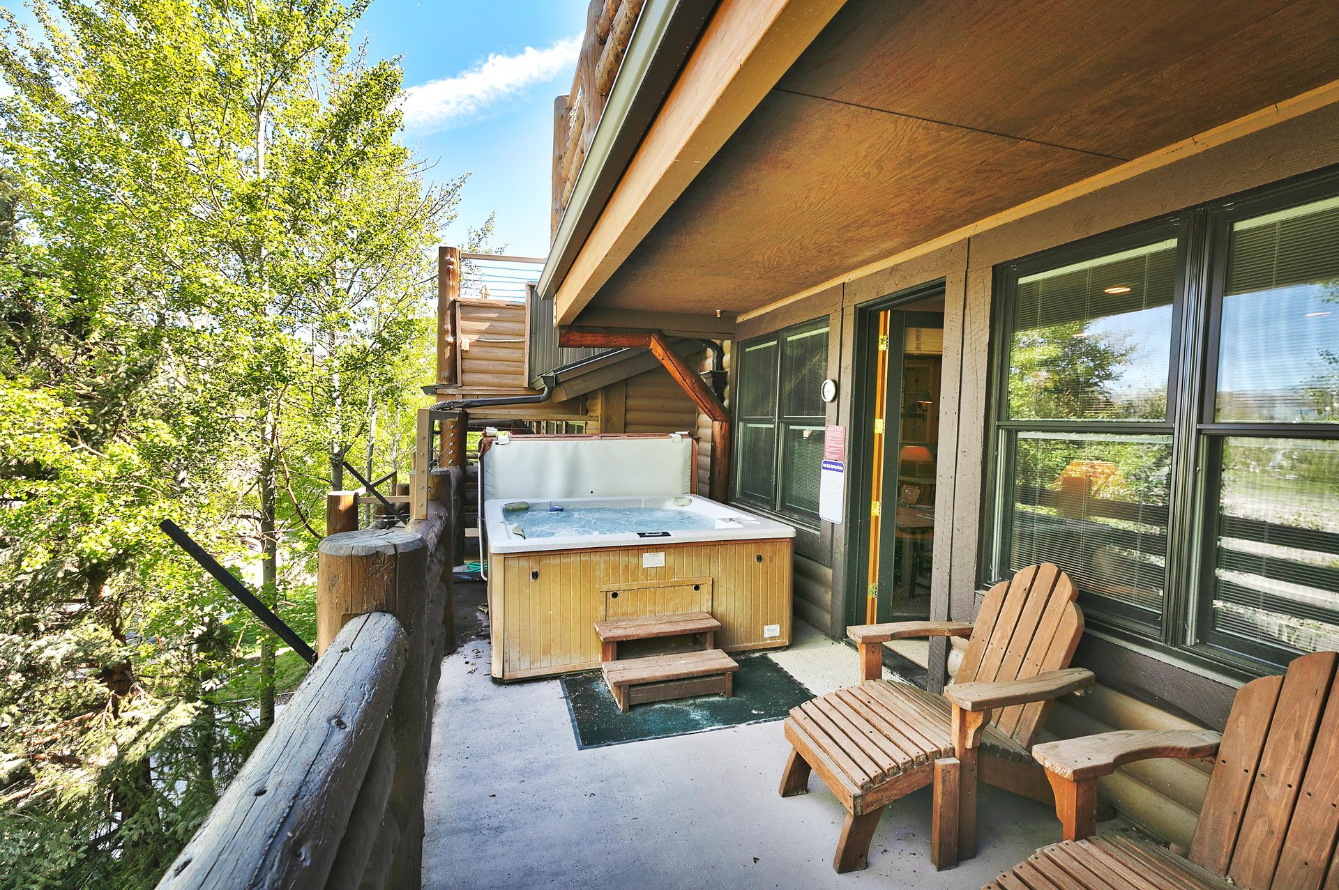 Spacious private deck with jacuzzi and wooden Adirondack lounge chairs