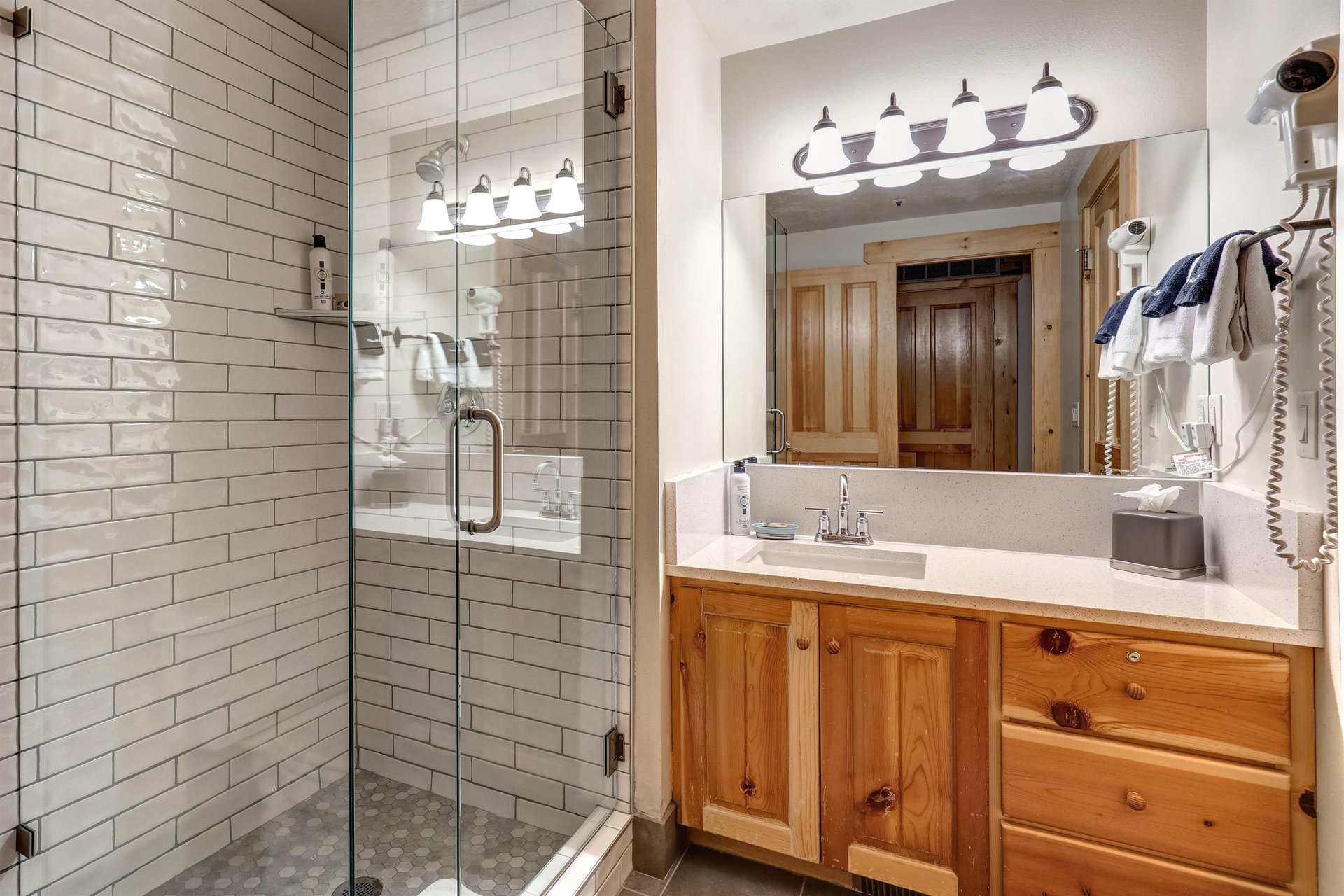 Second bathroom with walk in tiled shower and single sink vanity.