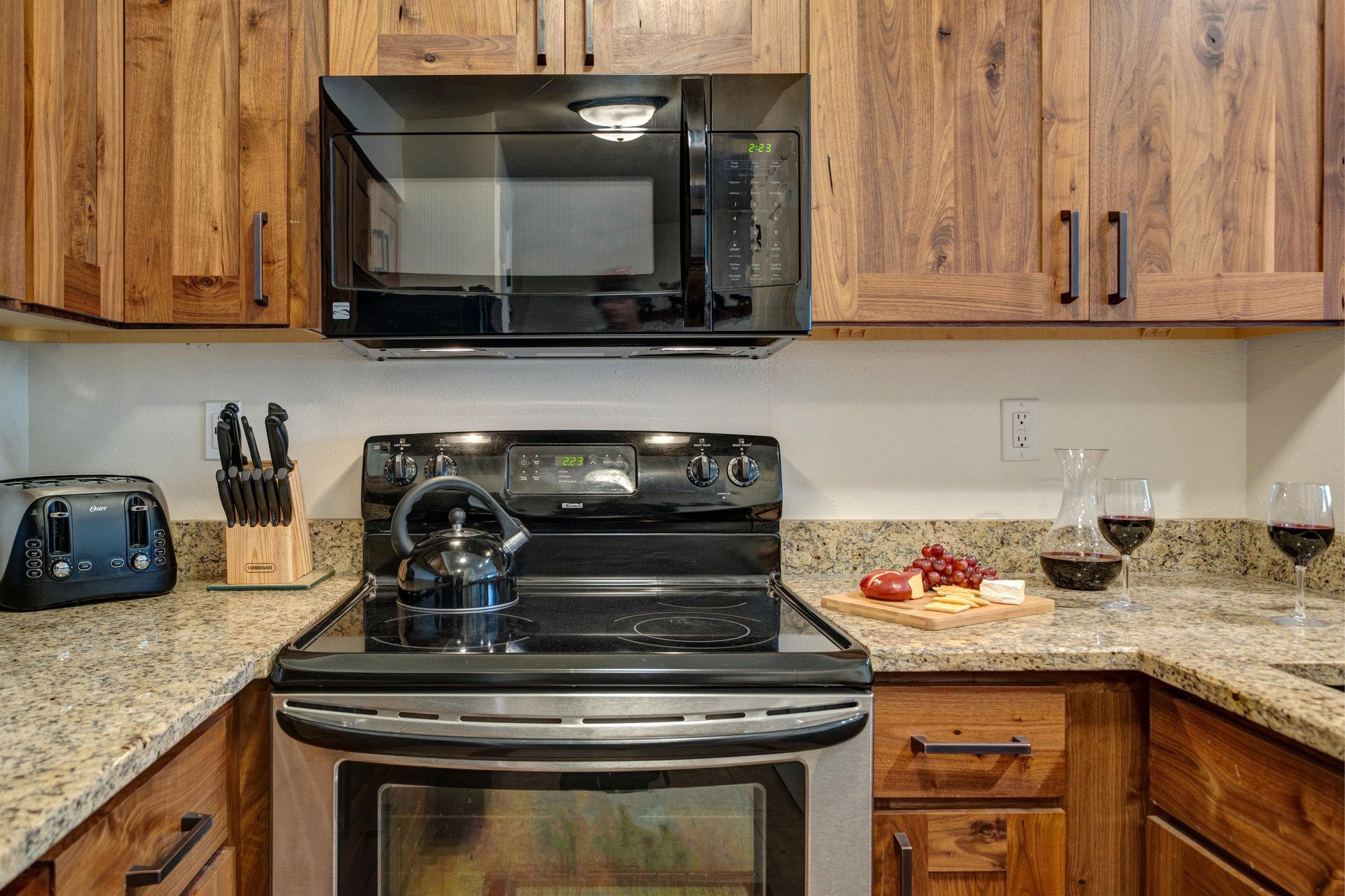 The kitchen has a stainless steel oven, black microwave and wooden cabinets.