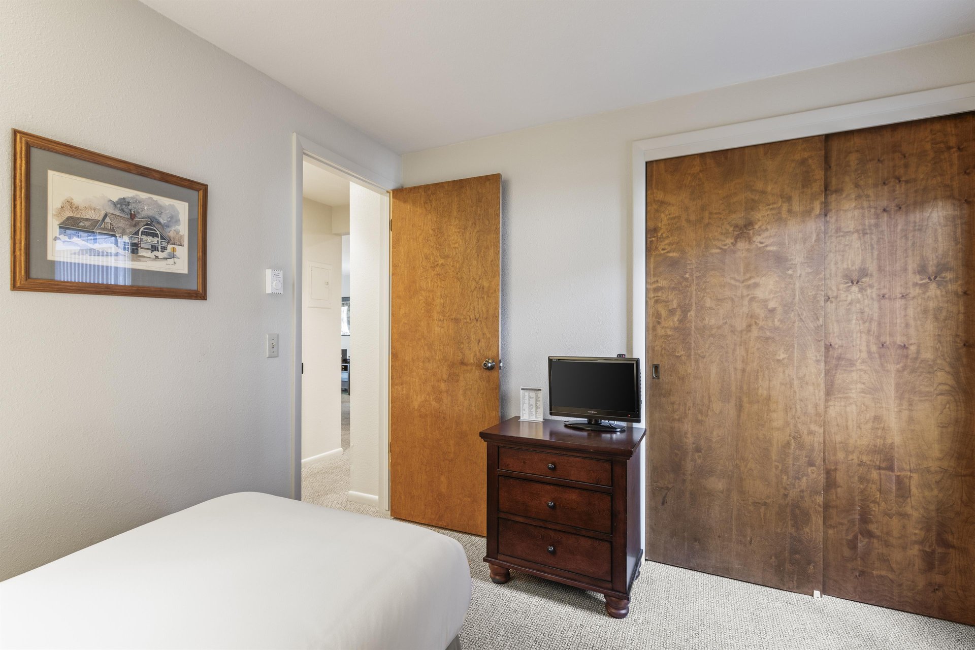 Snow Flower 135s second bedroom with twin beds with white linens and a small wooden cabinet with TV.