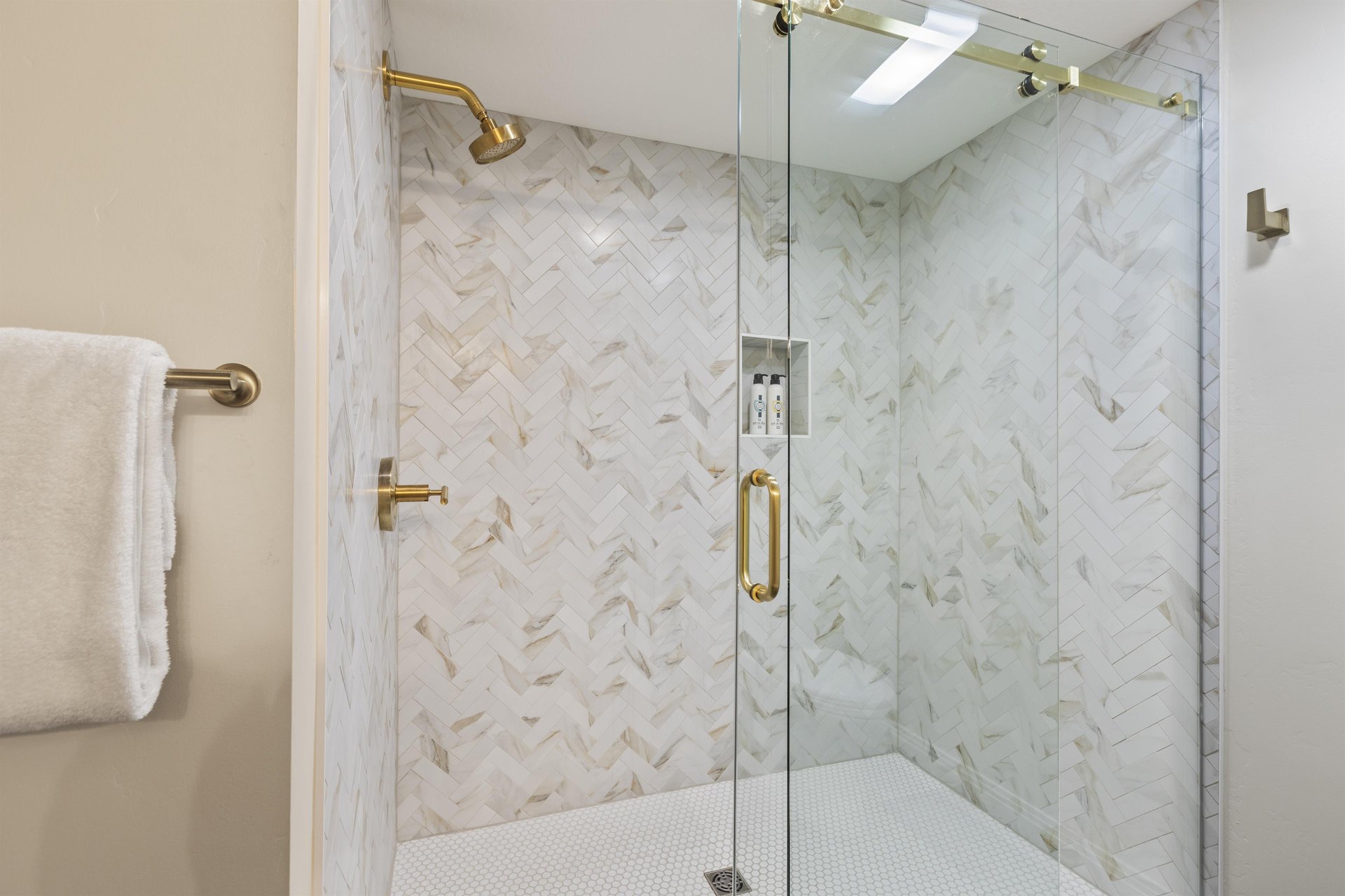 The en suite bathroom with walkin shower with glass doors and brass hardware.