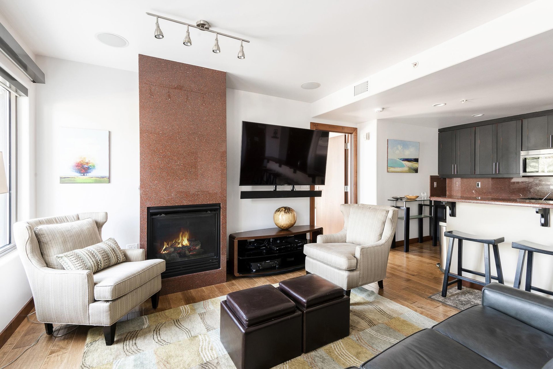 Beautifully appointed living room, hardwood floors, large flat screen wall mounted TV, and gas fireplace with 2 accent chairs