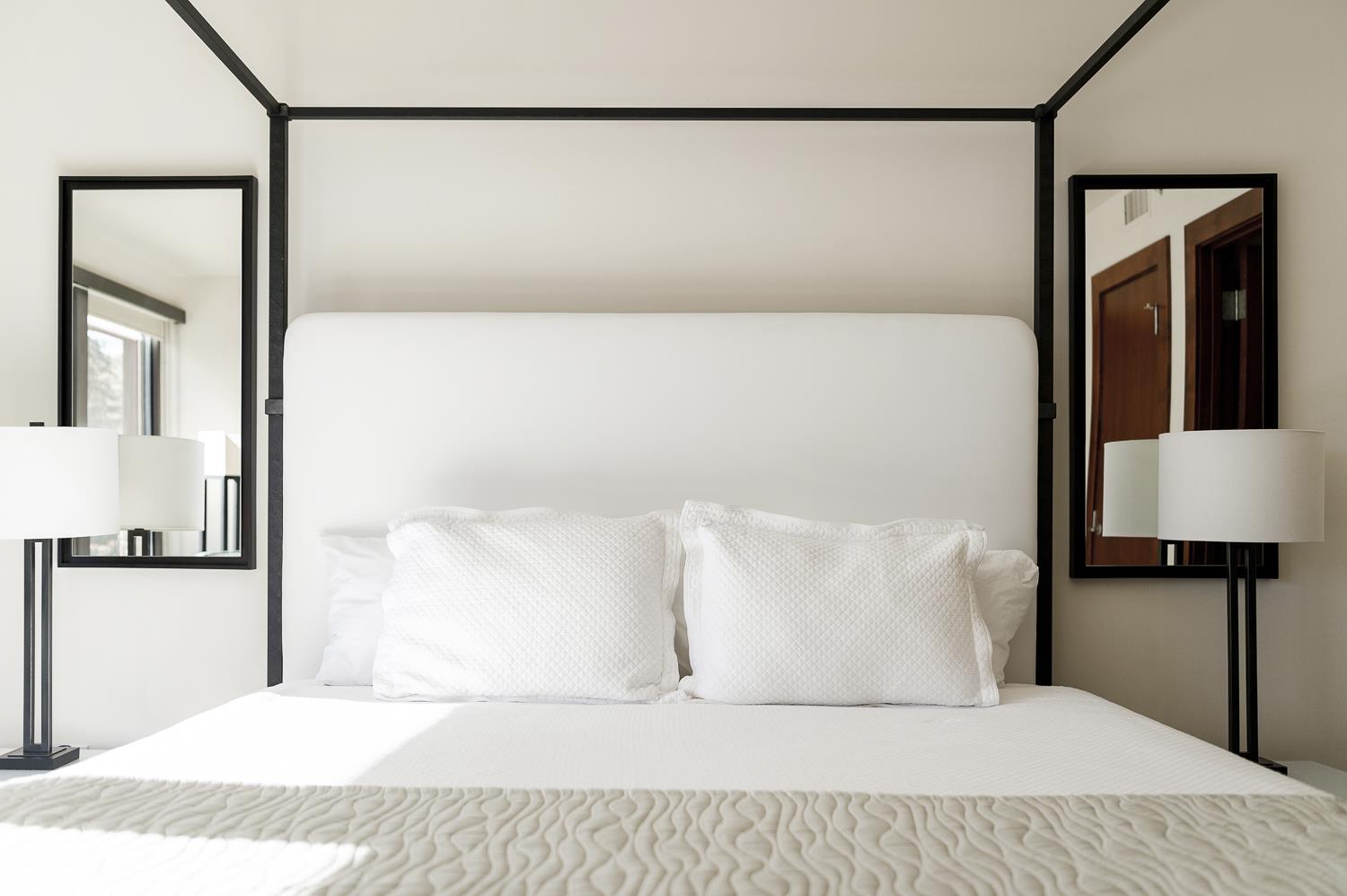 Lush king bed in the main bedroom with white quilt and linens and light green quilt accent cover