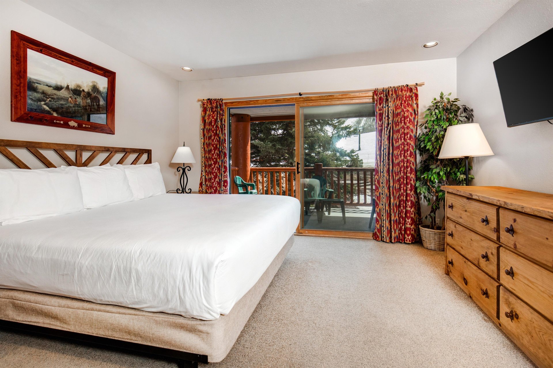 Snow Flower 20s main suite has a kingsize bed and wooden furnishings and sliding glass doors to a private patio.